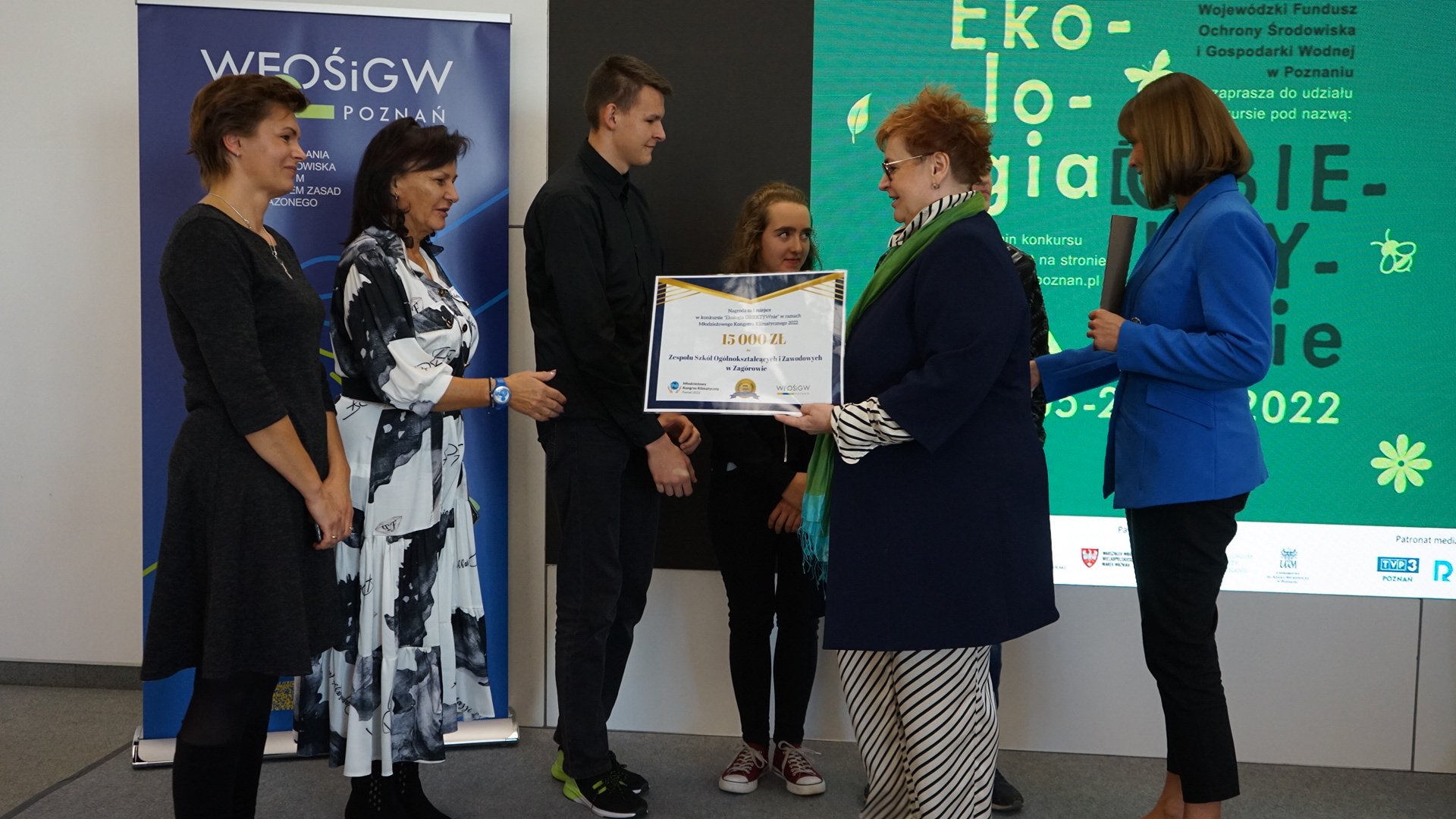 6 osób stoi na tle ściany.