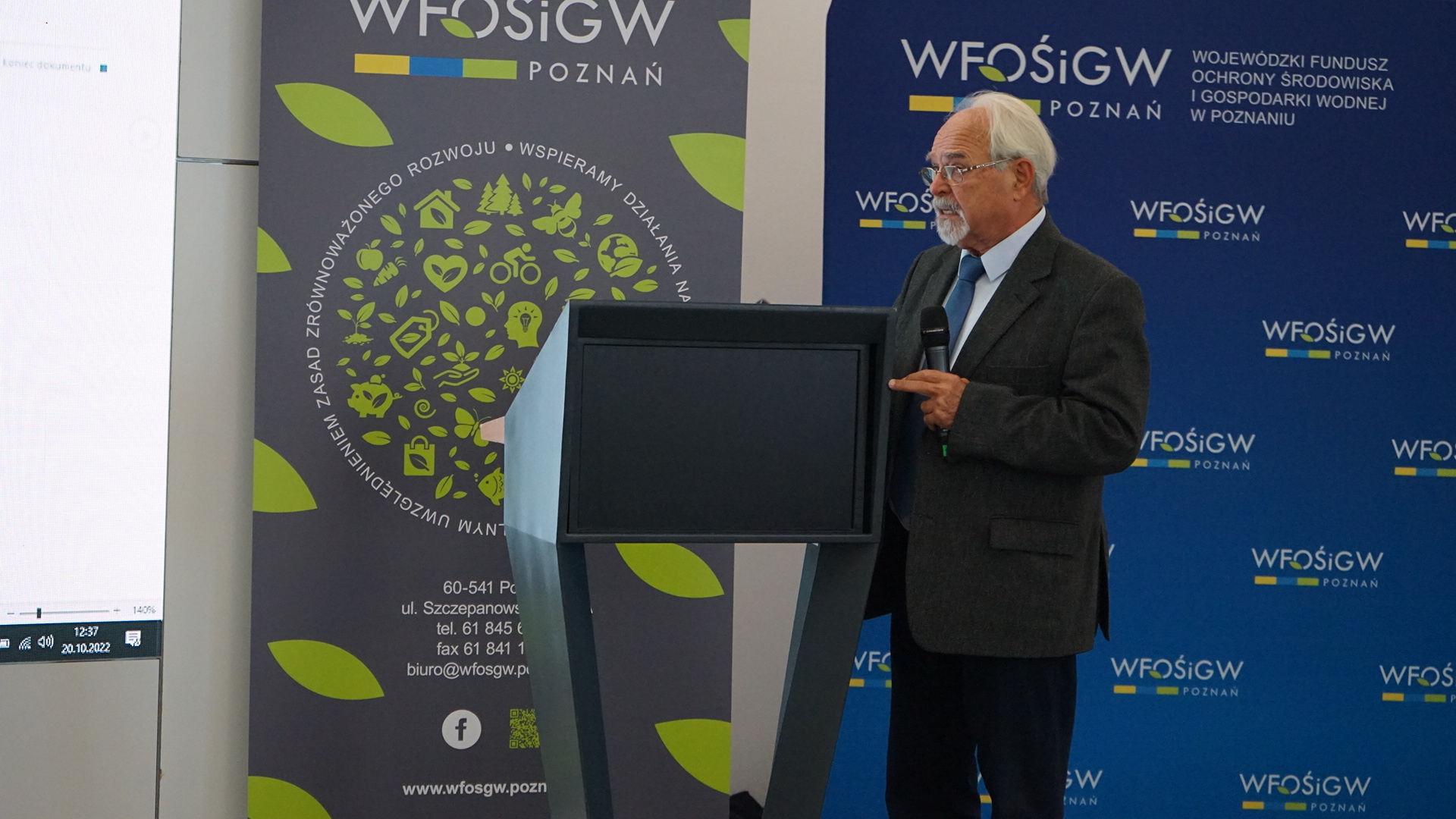 Jedna osoba stoi na scenie przy mównicy.