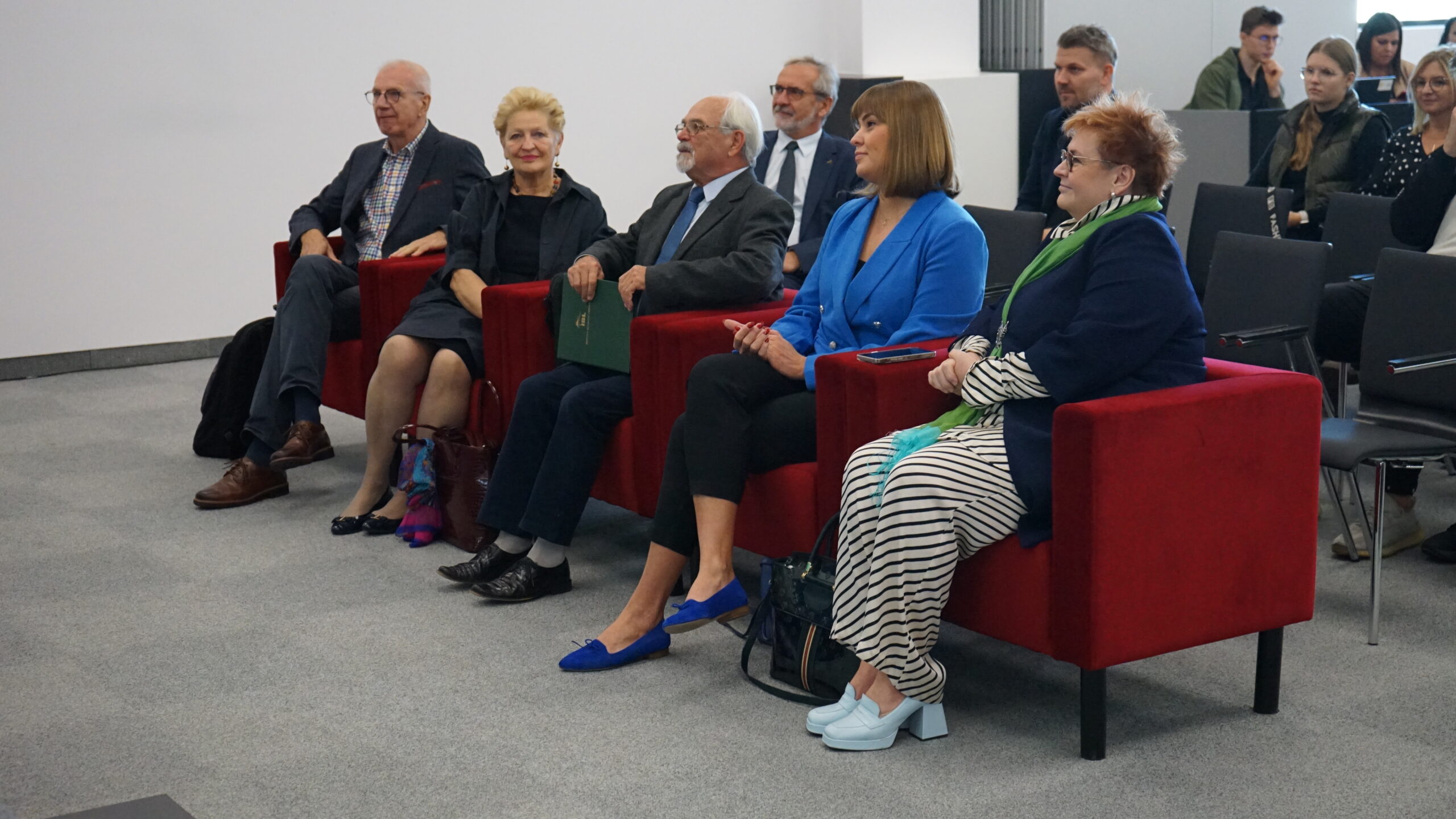 4 osoby siedzą na widowni.