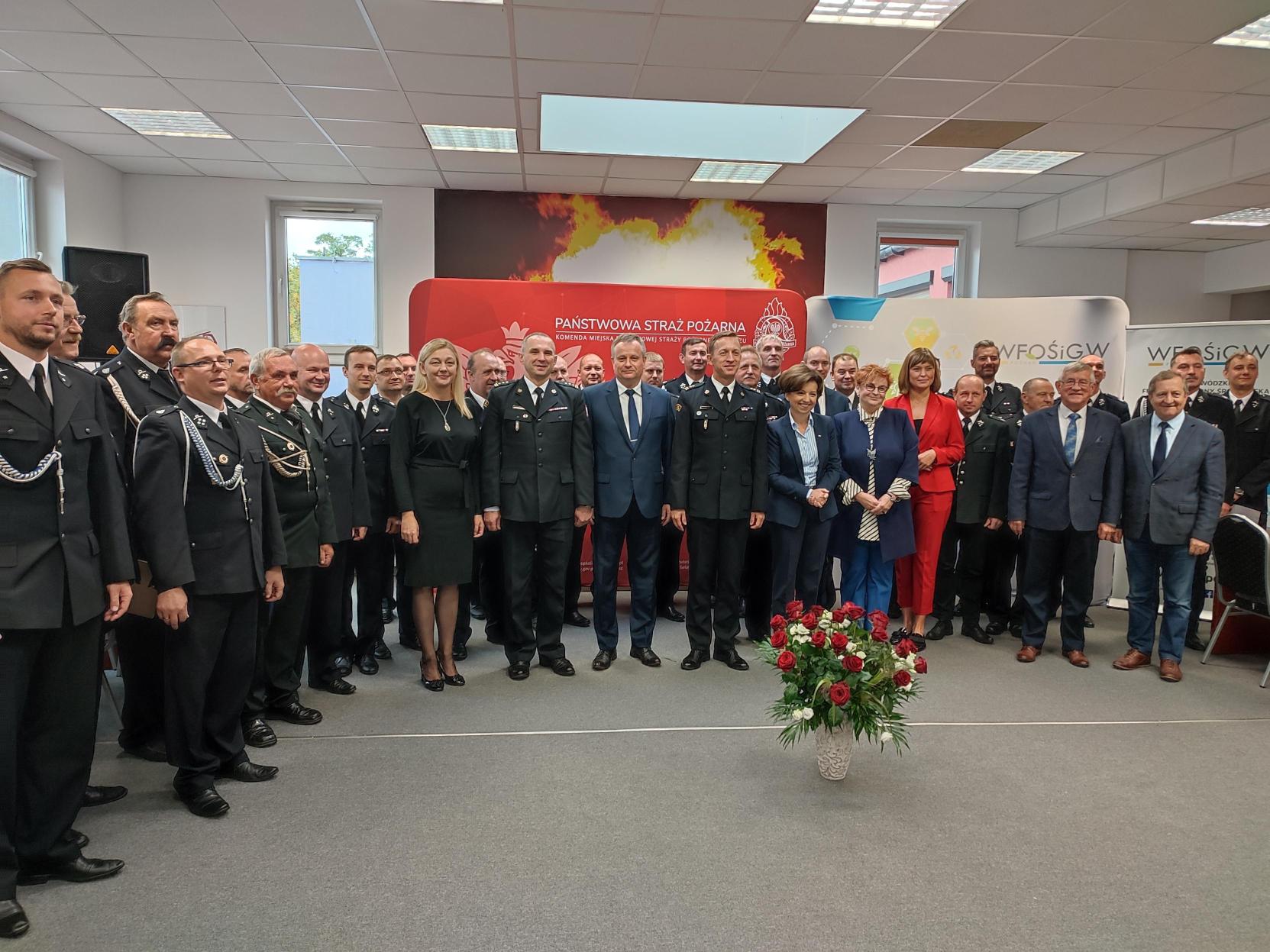 Grupa ludzi stoi na środku sali.