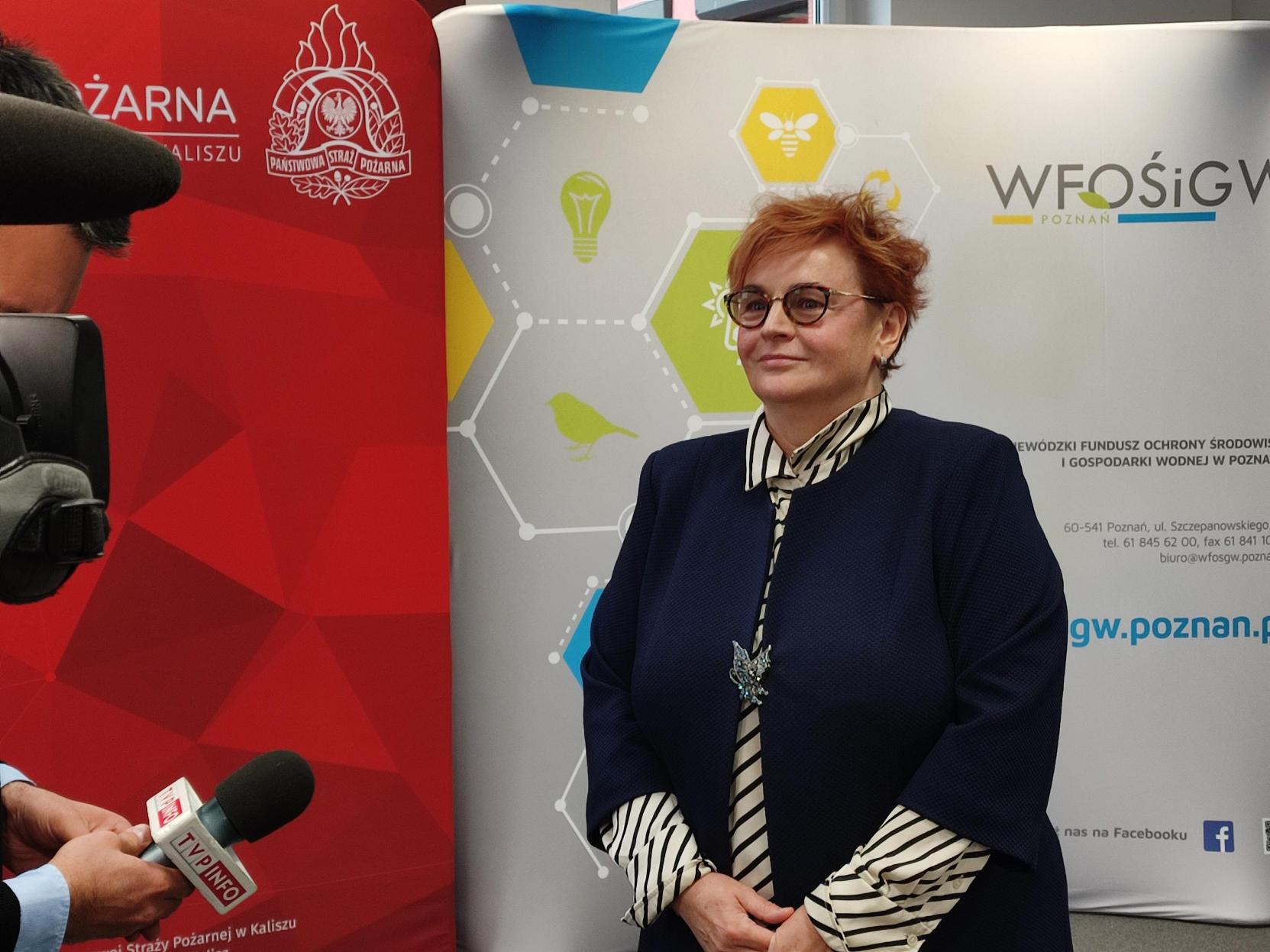 1 osoba stoi na tle ściany.