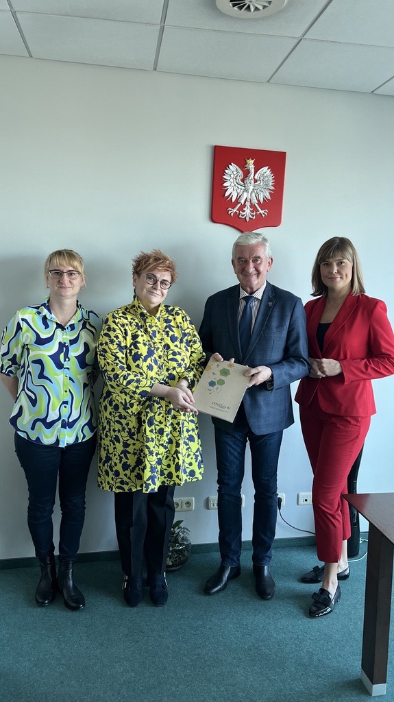 4 osoby stoją na tle ściany.