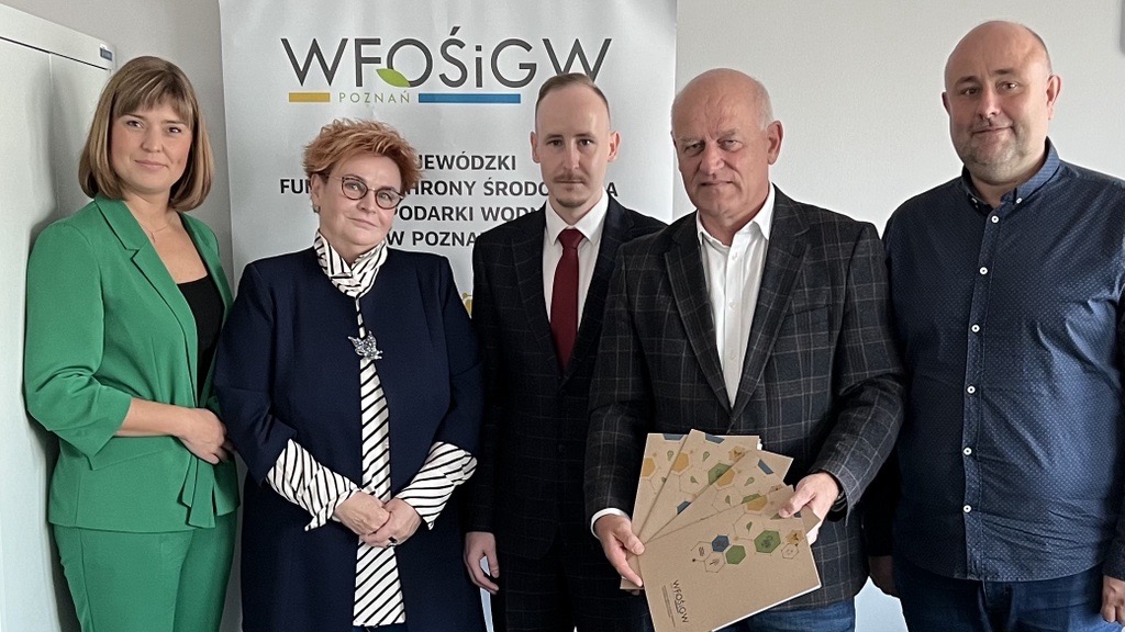 5 osób stoi na tle ściany.