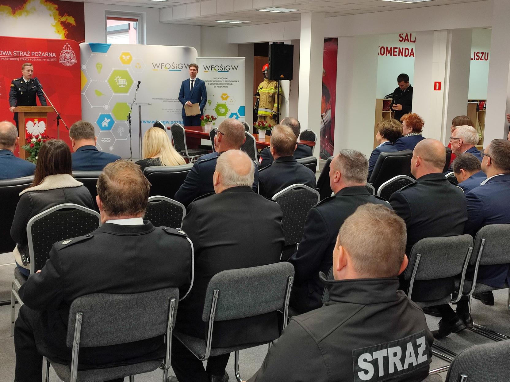 Ludzie siedzą na krzesłach na sali.