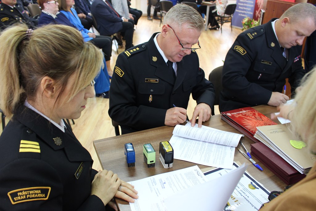 3 osoby siedzą przy stole.