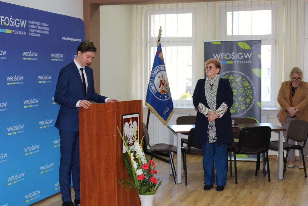 1 osoba stoi przy mównicy.