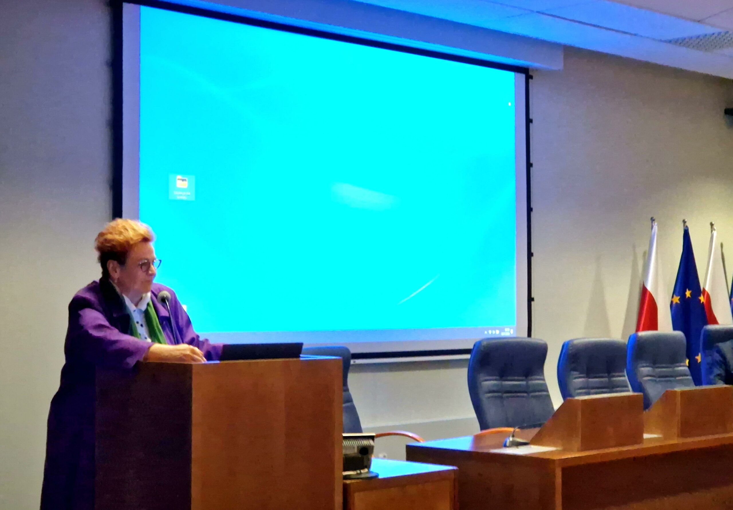 1 osoba stoi przy mównicy.