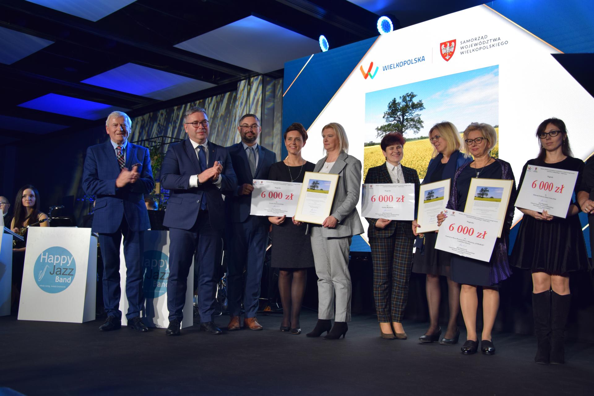 Grupa ludzi stoi na scenie.