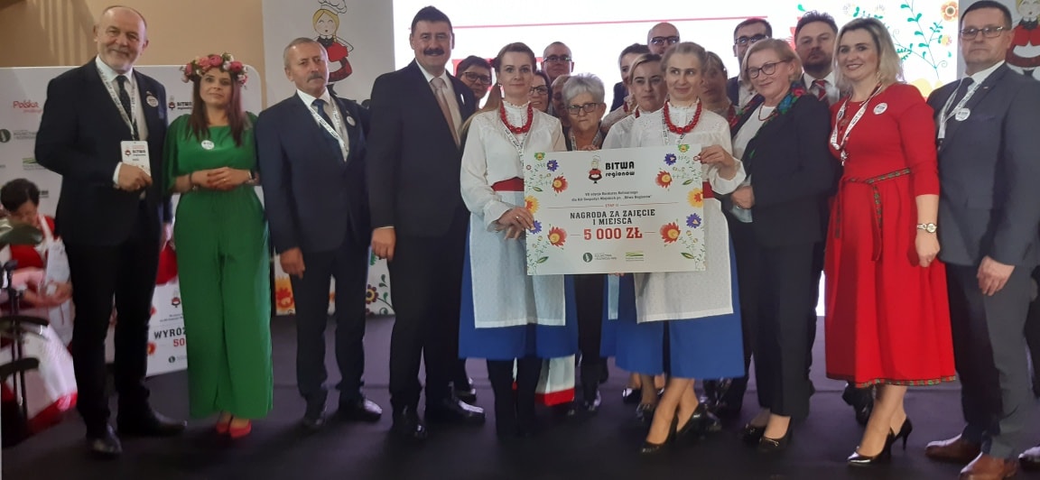 Duża grupa osób stoi na scenie.