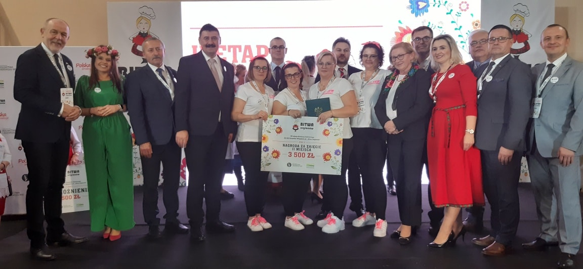 Duża grupa osób stoi na scenie.