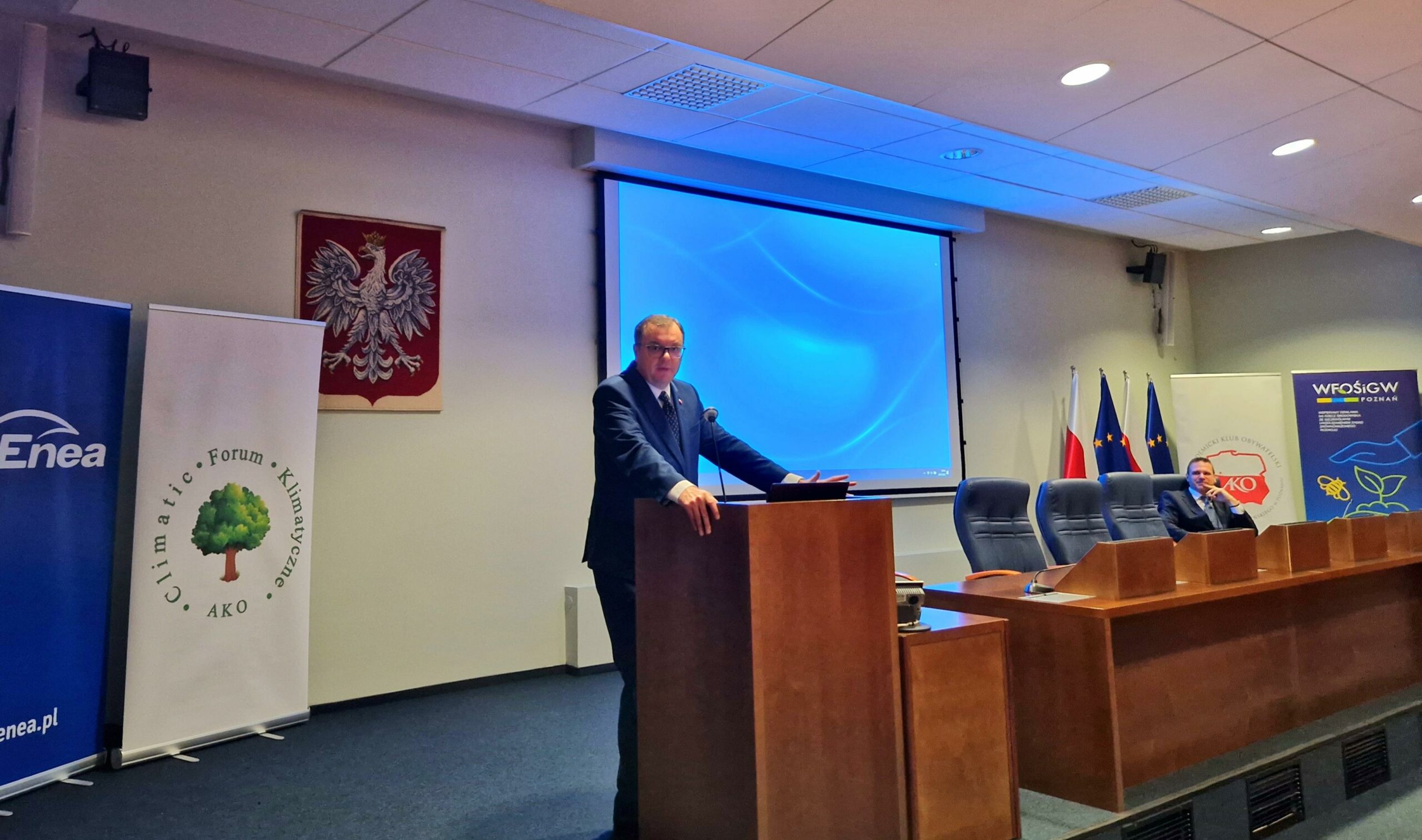 1 osoba stoi przy mównicy.