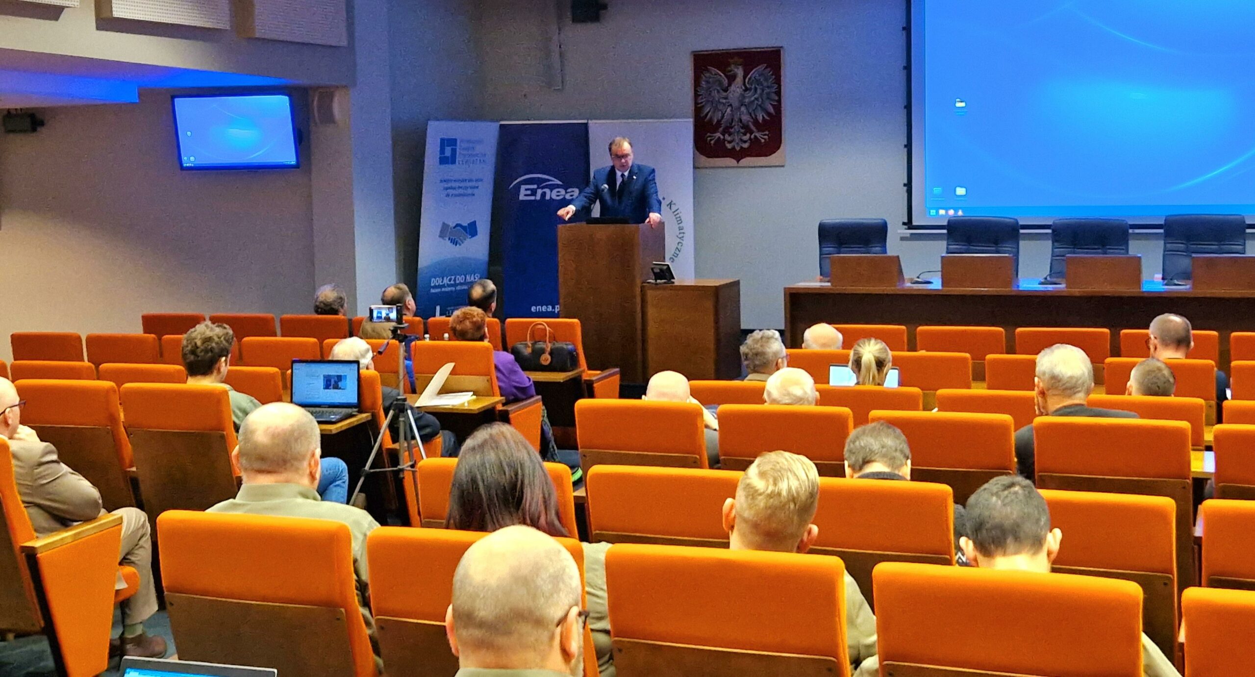 Widok sali i 1 osoba stoi przy mównicy.