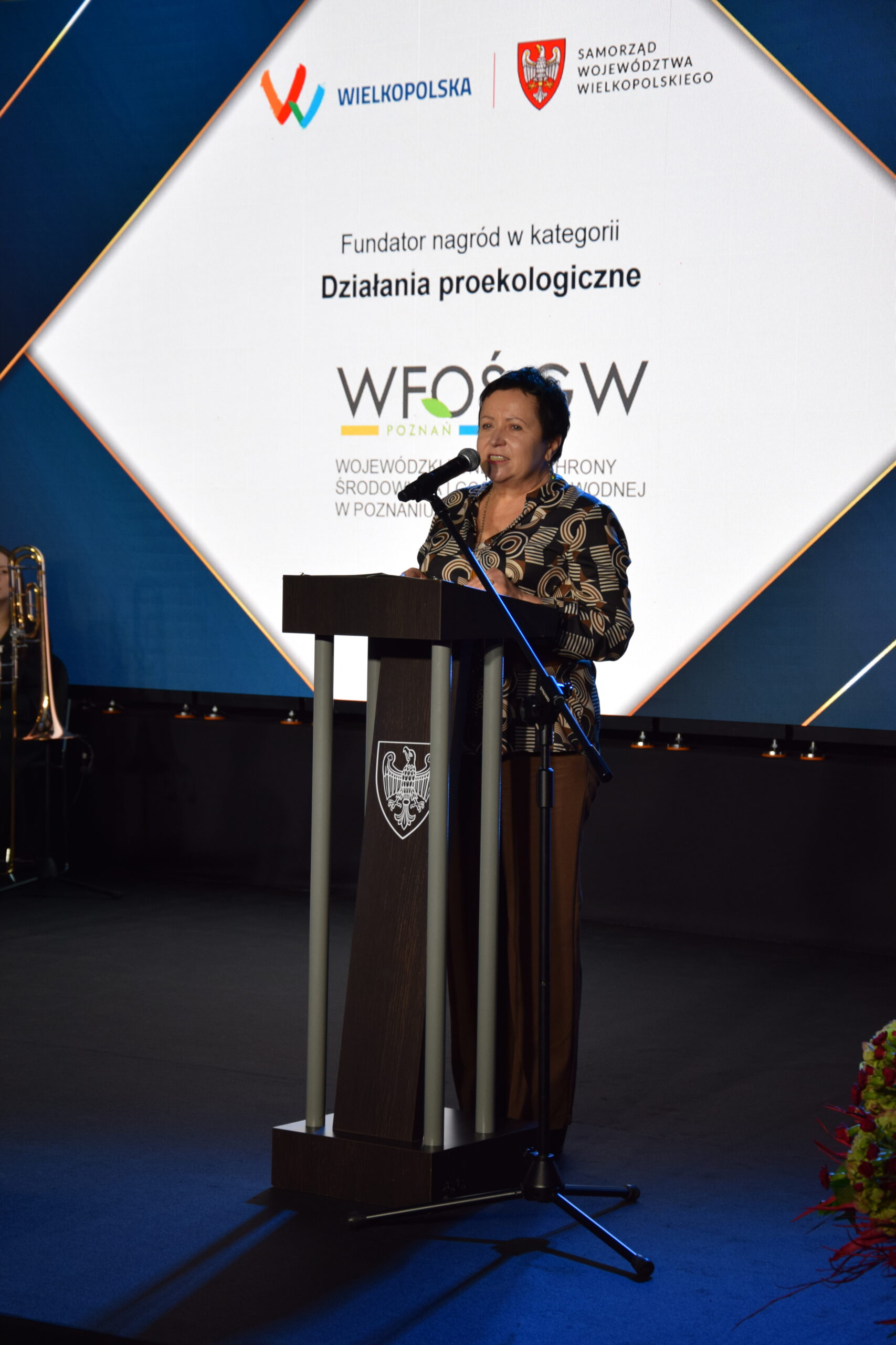 Osoba stoi przy mównicy.