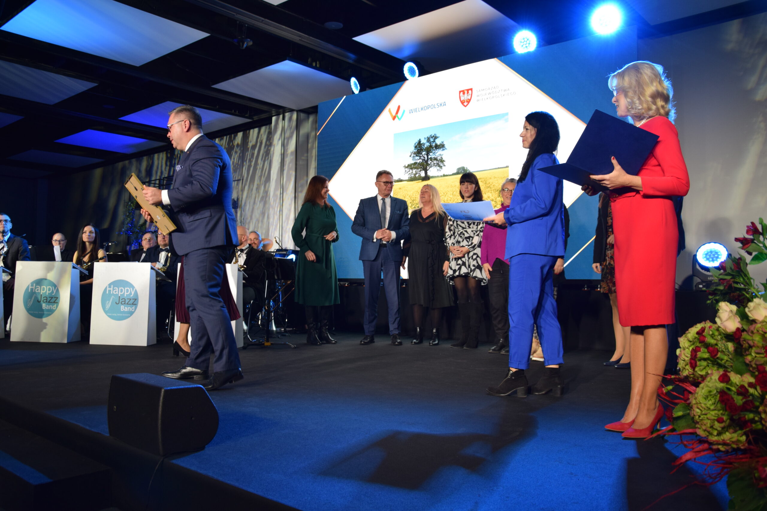 Grupa ludzi stoi na scenie.