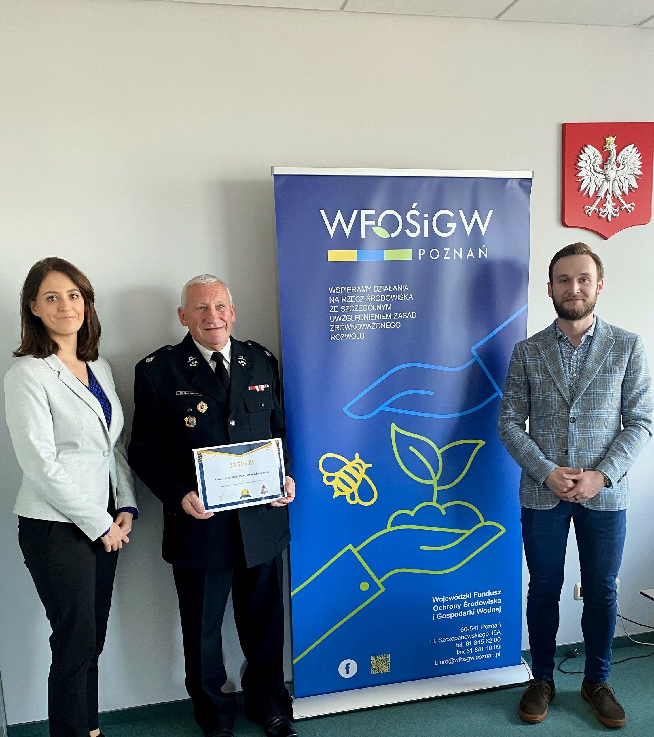 3 osoby stoją na tle ściany.