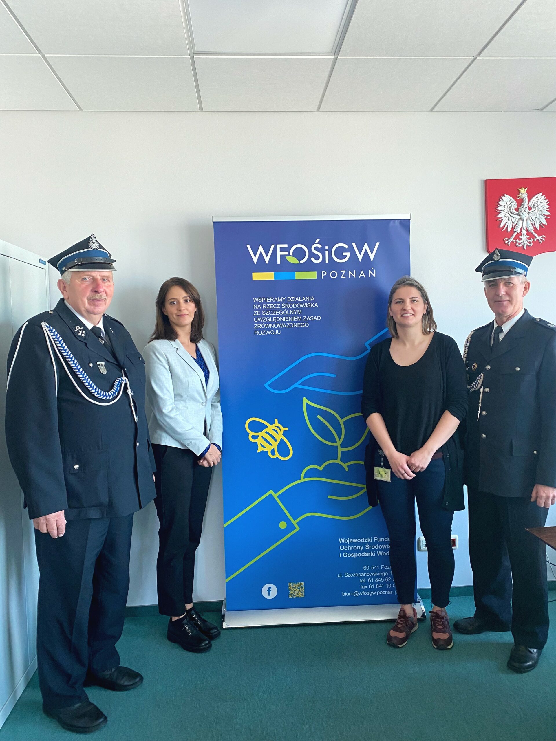 4 osoby stoją na tle ściany.