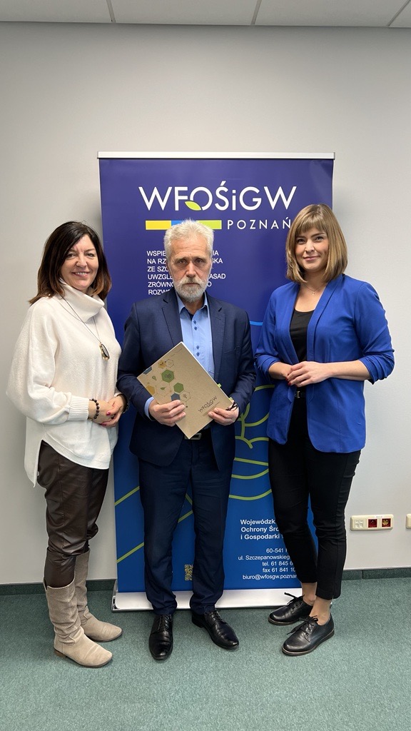 3 osoby stoją na tle ściany.