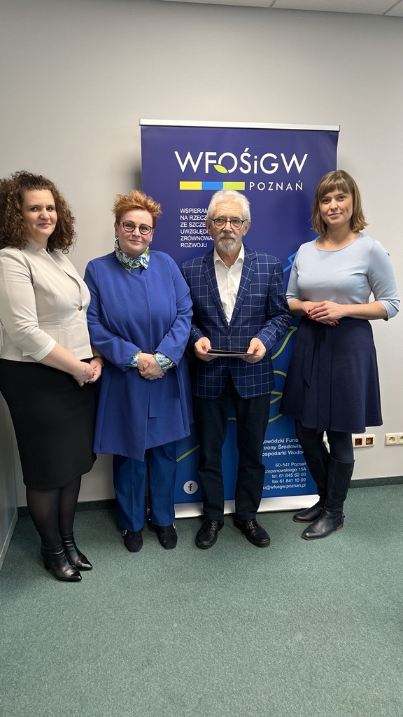 4 osoby stoją na tle ściany