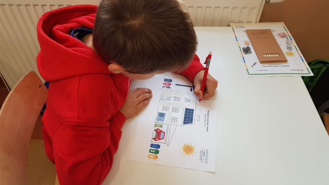 Chłopiec rysuje kredkami.