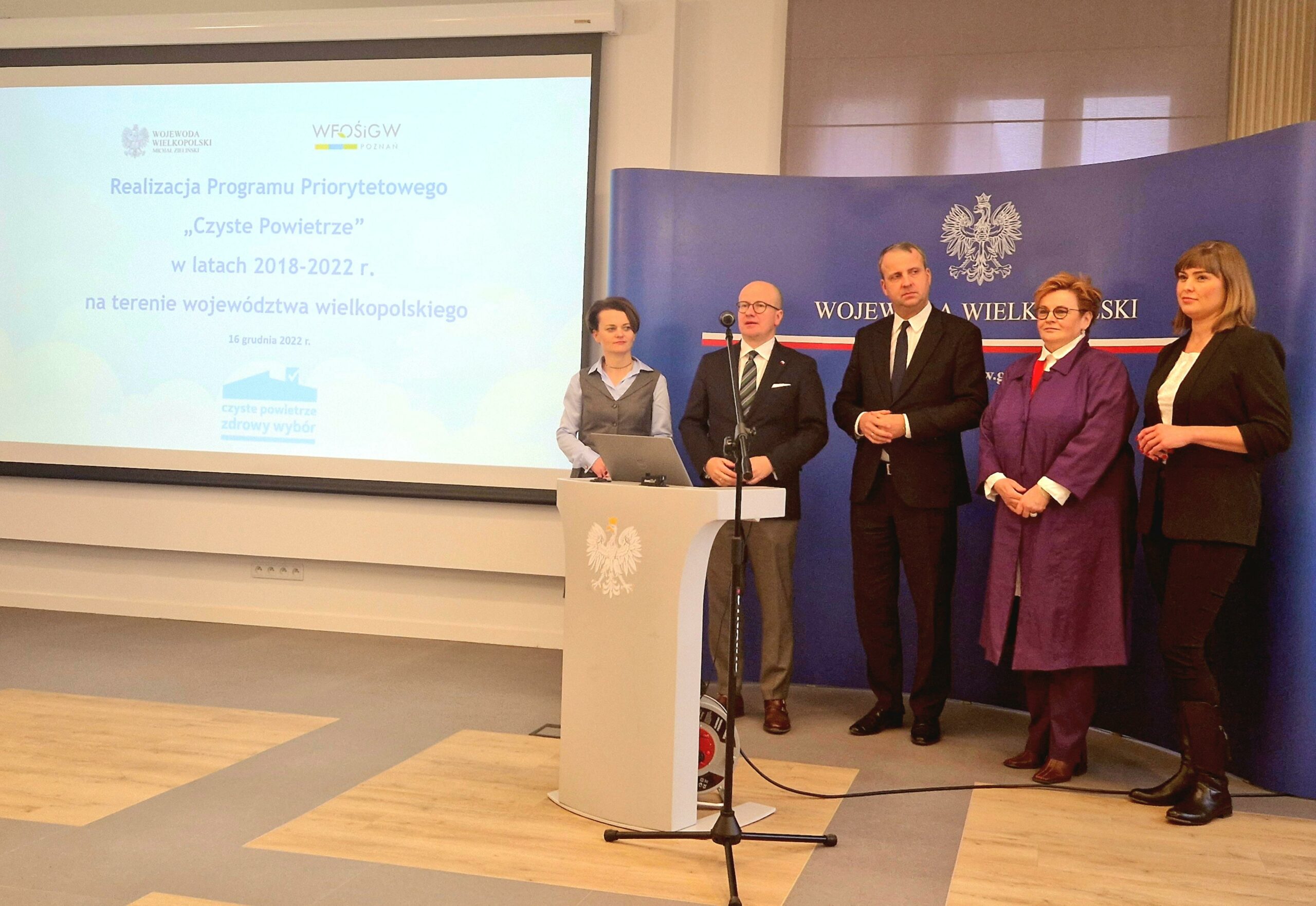 Na zdjęciu znajduje się 5 osób na tle niebieskiej ścianki reklamowej.