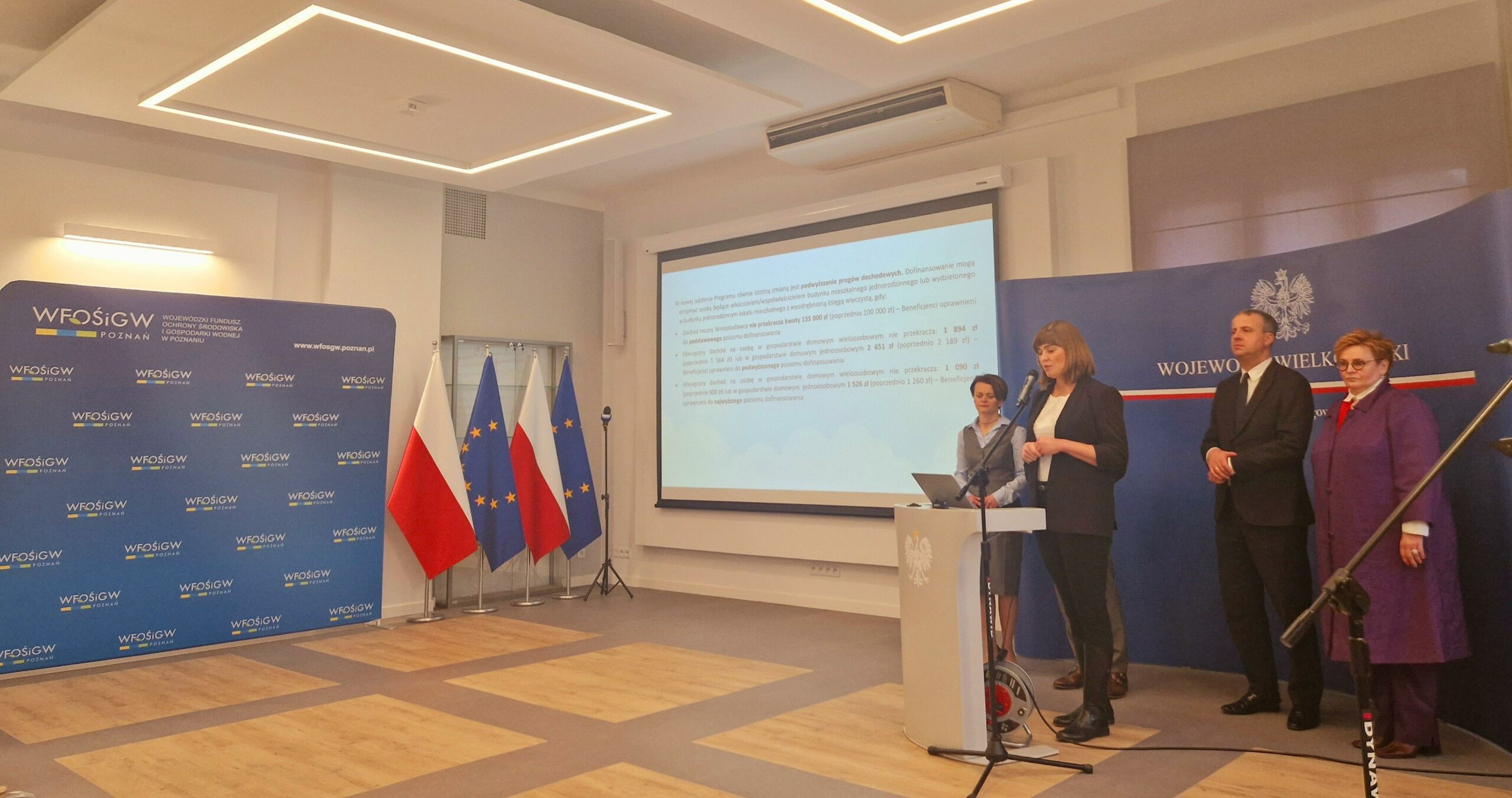 Na zdjęciu jedna osoba stoi przy mównicy, a pozostałe 4 osoby stoją w tle.