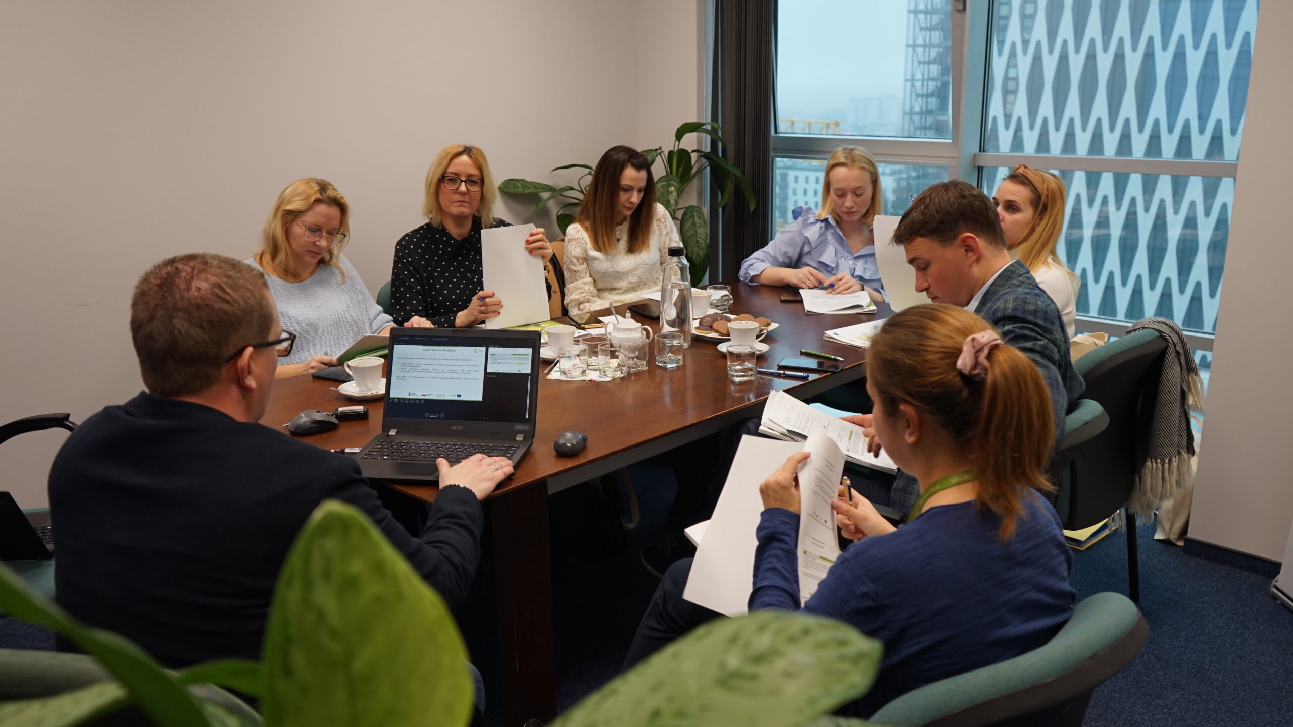 Na zdjęciu 8 osób siedzi wokół dużego stołu.