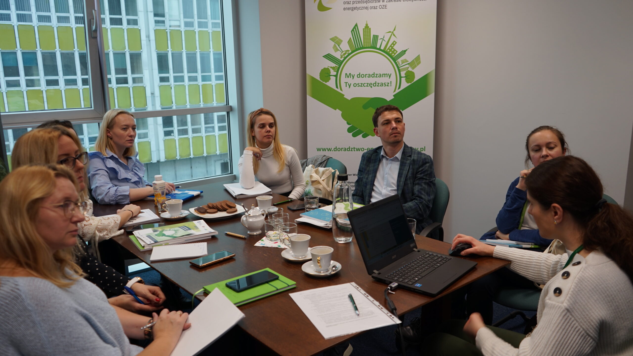 Na zdjęciu 8 osób siedzi wokół dużego stołu.