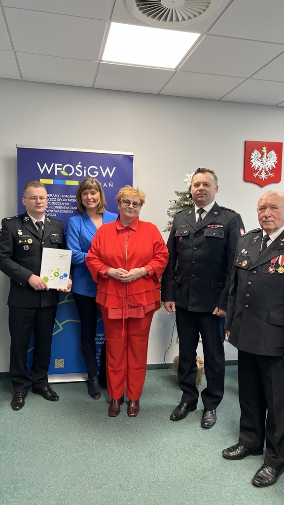 Na zdjęciu stoi 5 osób na tle bannera reklamowego.a