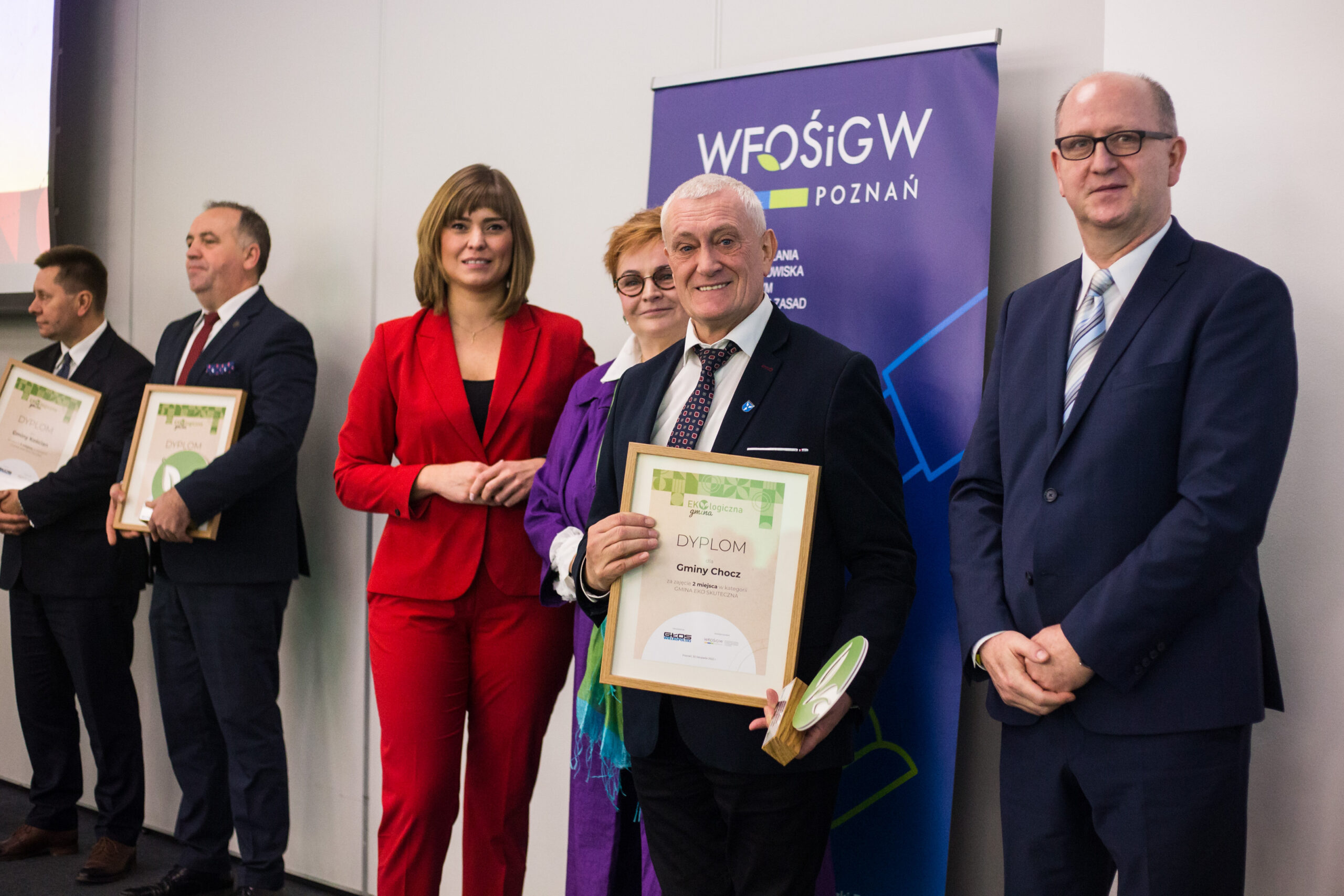 6 osób stoi na tle ściany.