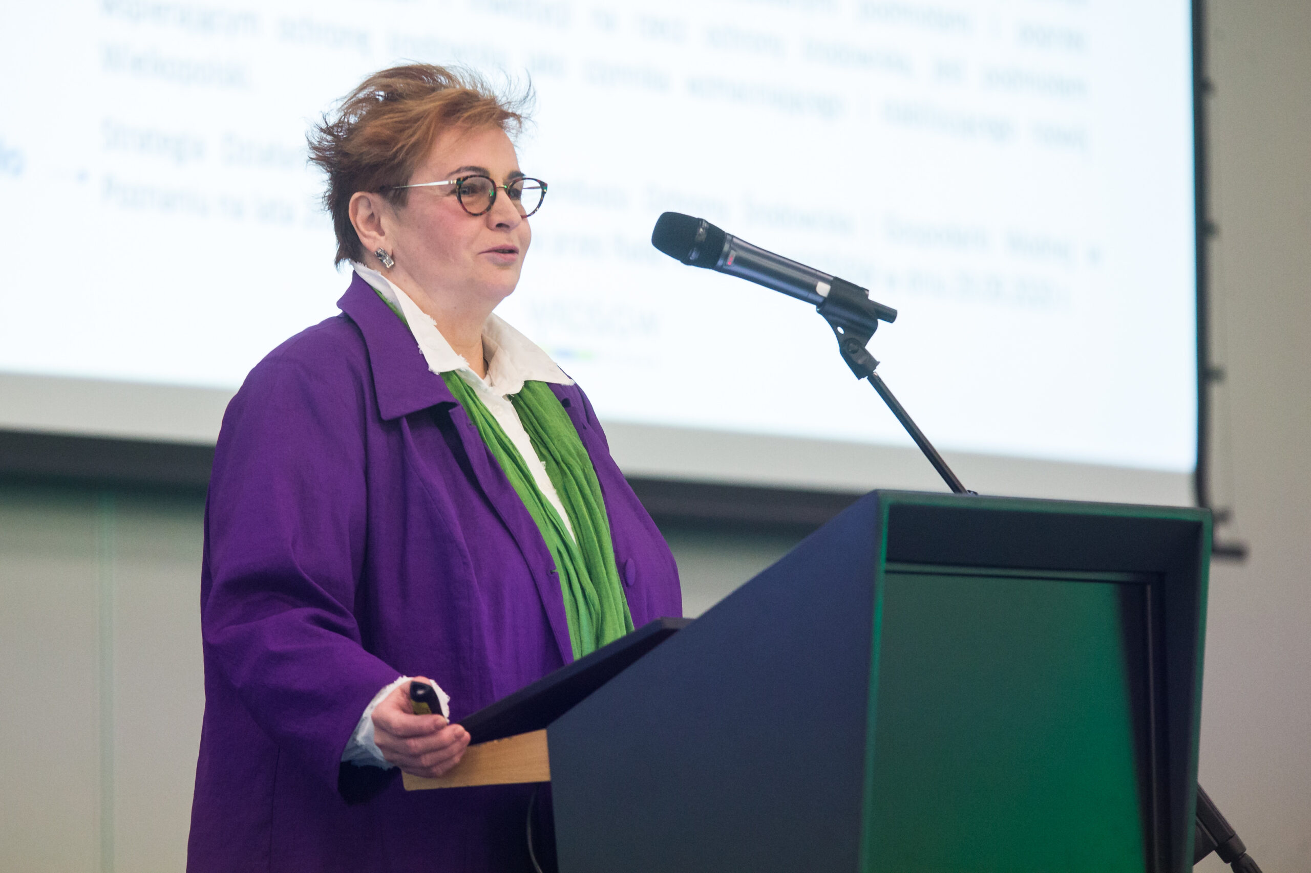 1 osoba stoi przy mównicy.