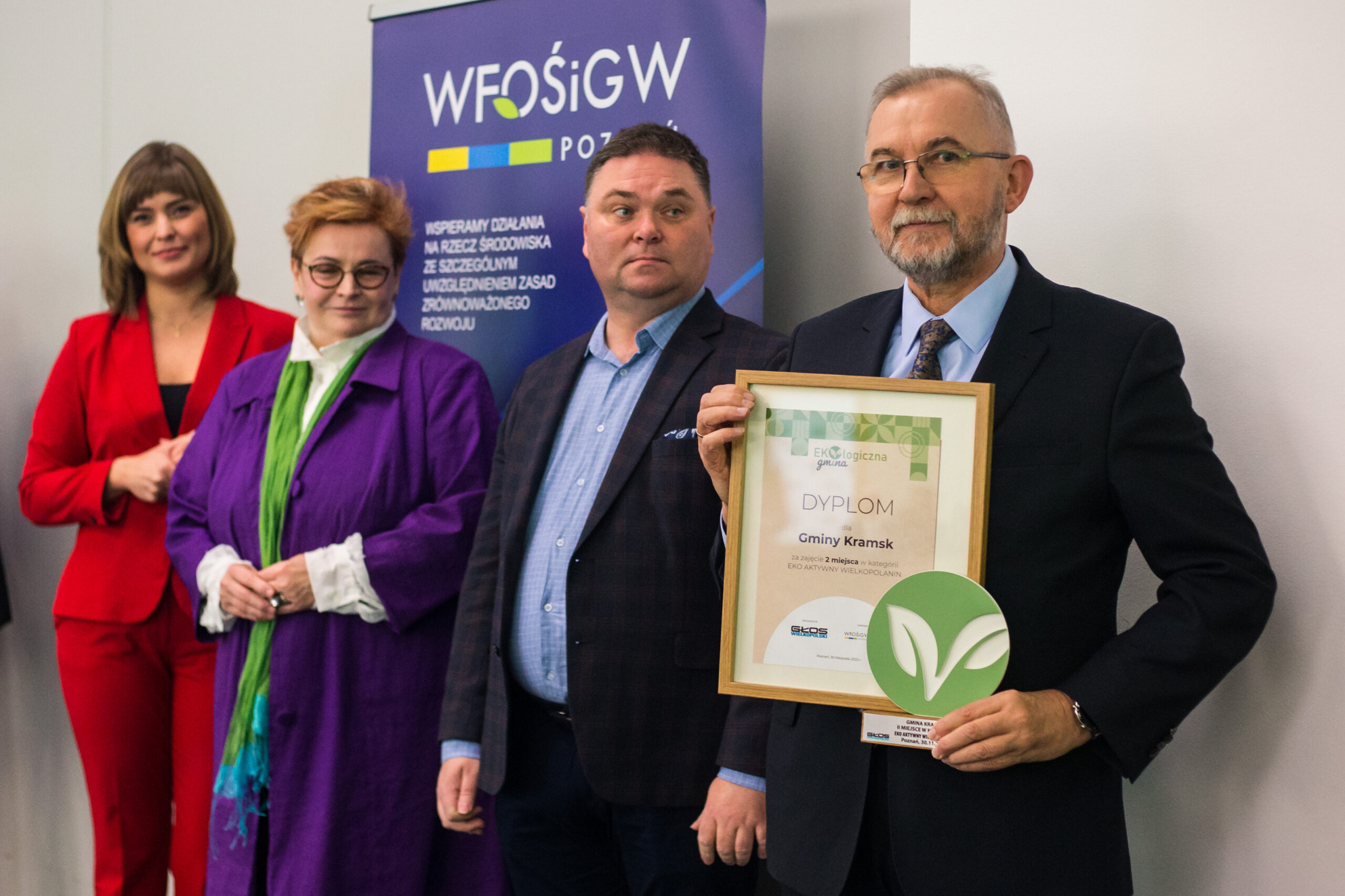 Cztery osoby stoją na tle ściany.