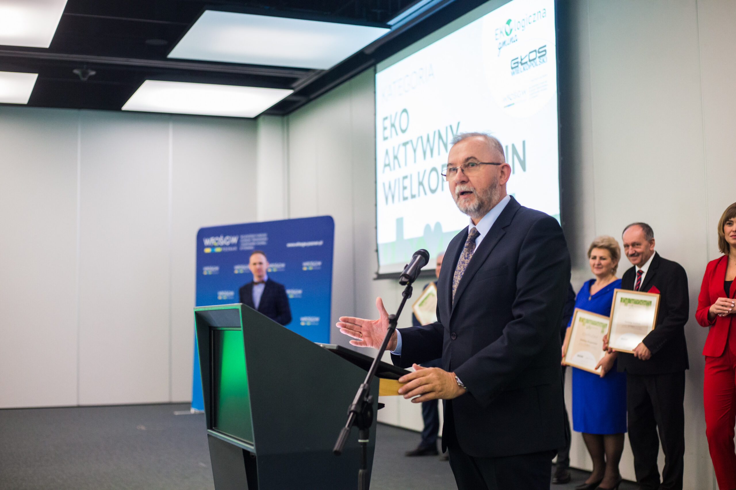 1 osoba stoi przy mównicy.