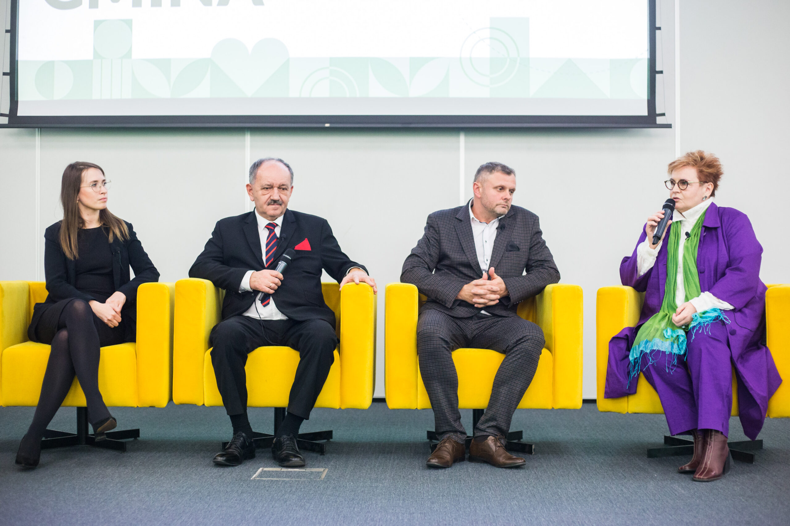 4 osoby siedzą na fotelach.