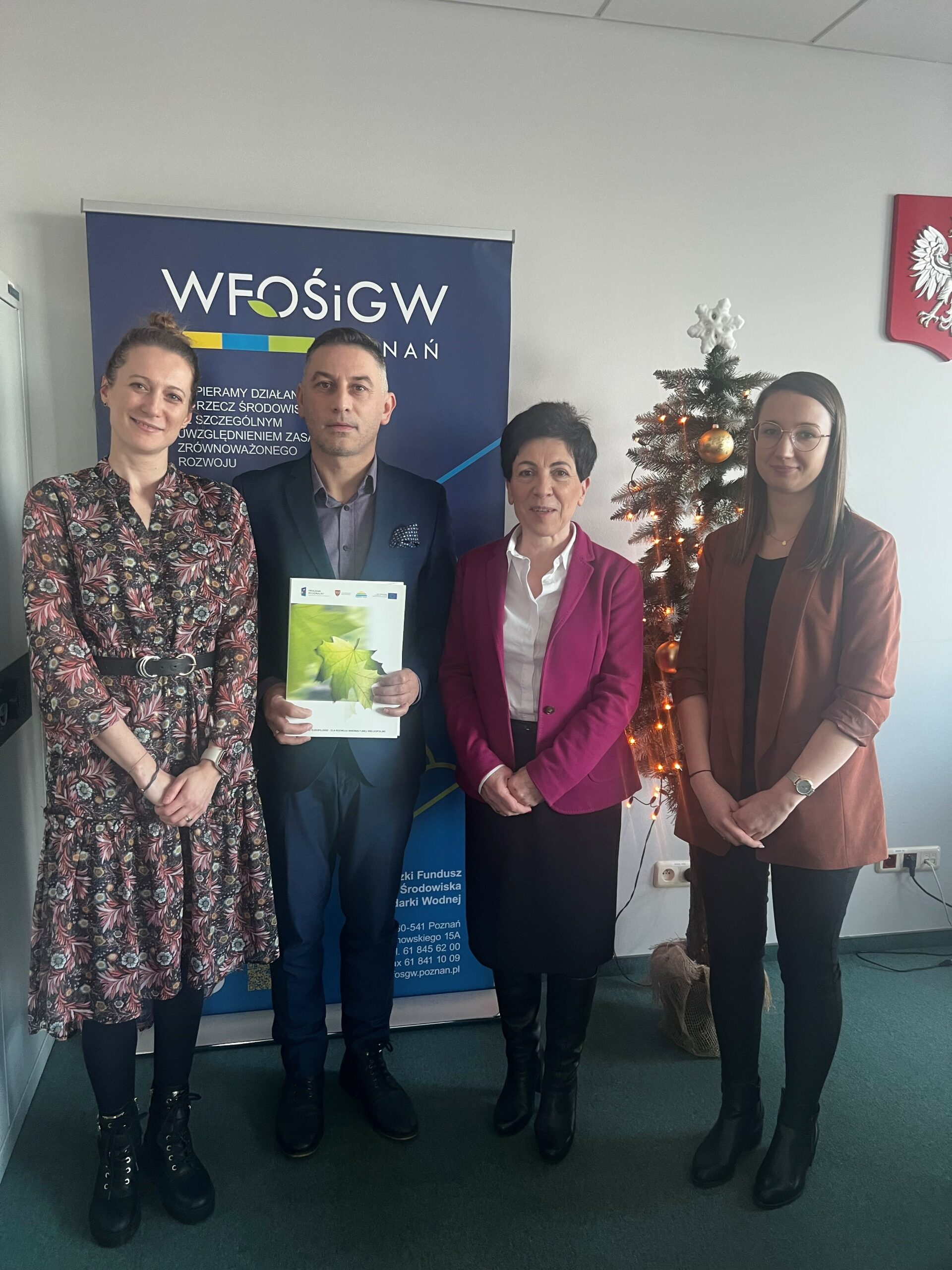 4 osoby stoją na tle ściany.