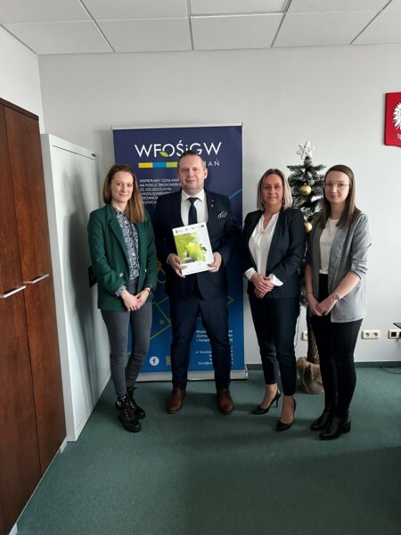 4 osoby stoją na tle ściany.