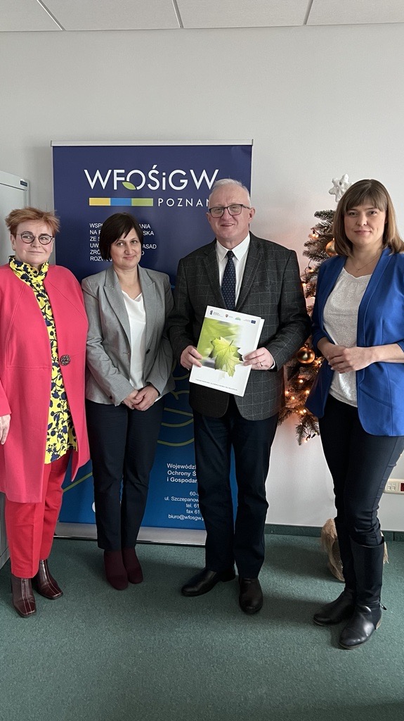 4 osoby stoją na tle ściany.