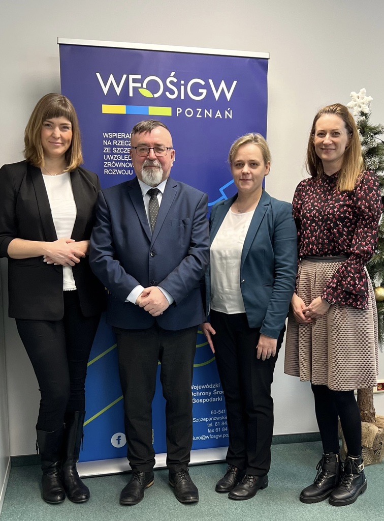 4 osoby stoją na tle ściany.