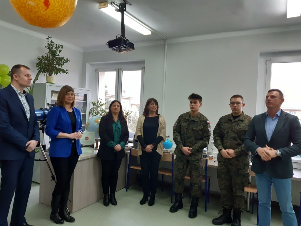 7 osób stoi w sali lekcyjnej