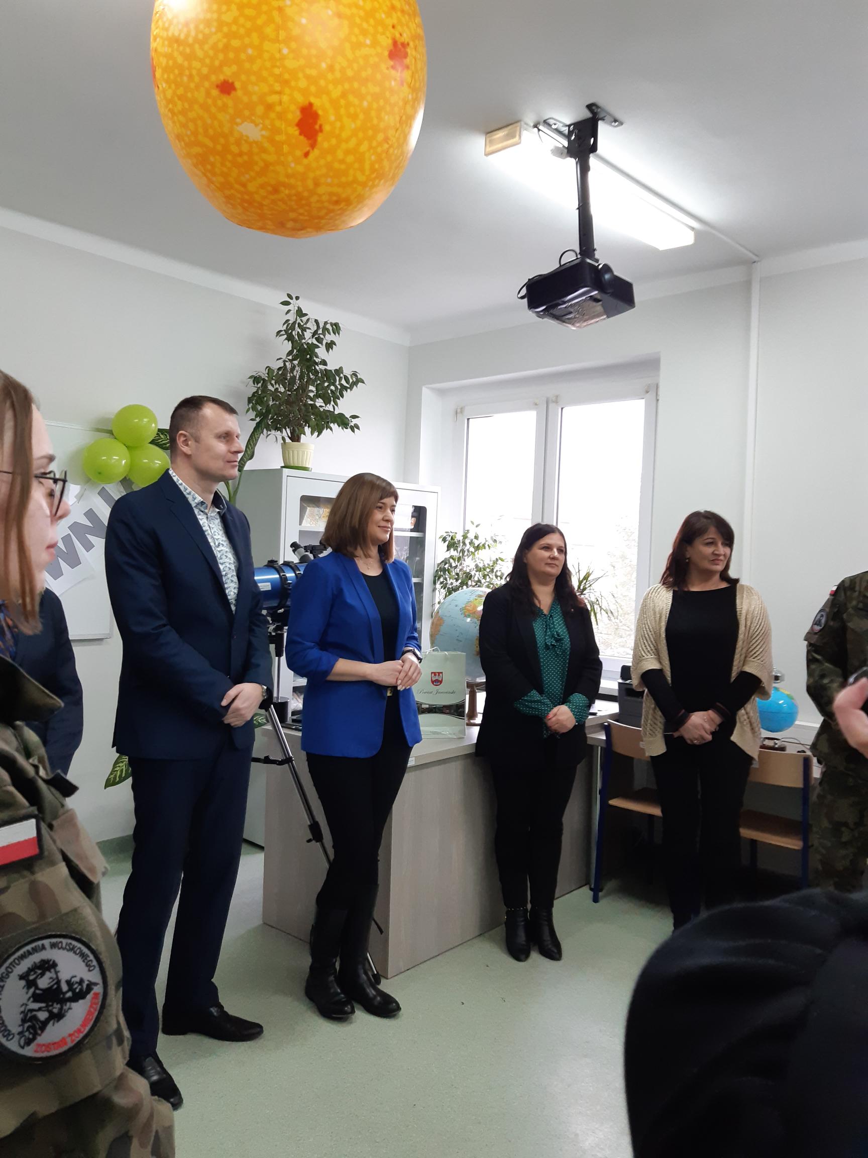 7 osób stoi w sali lekcyjnej