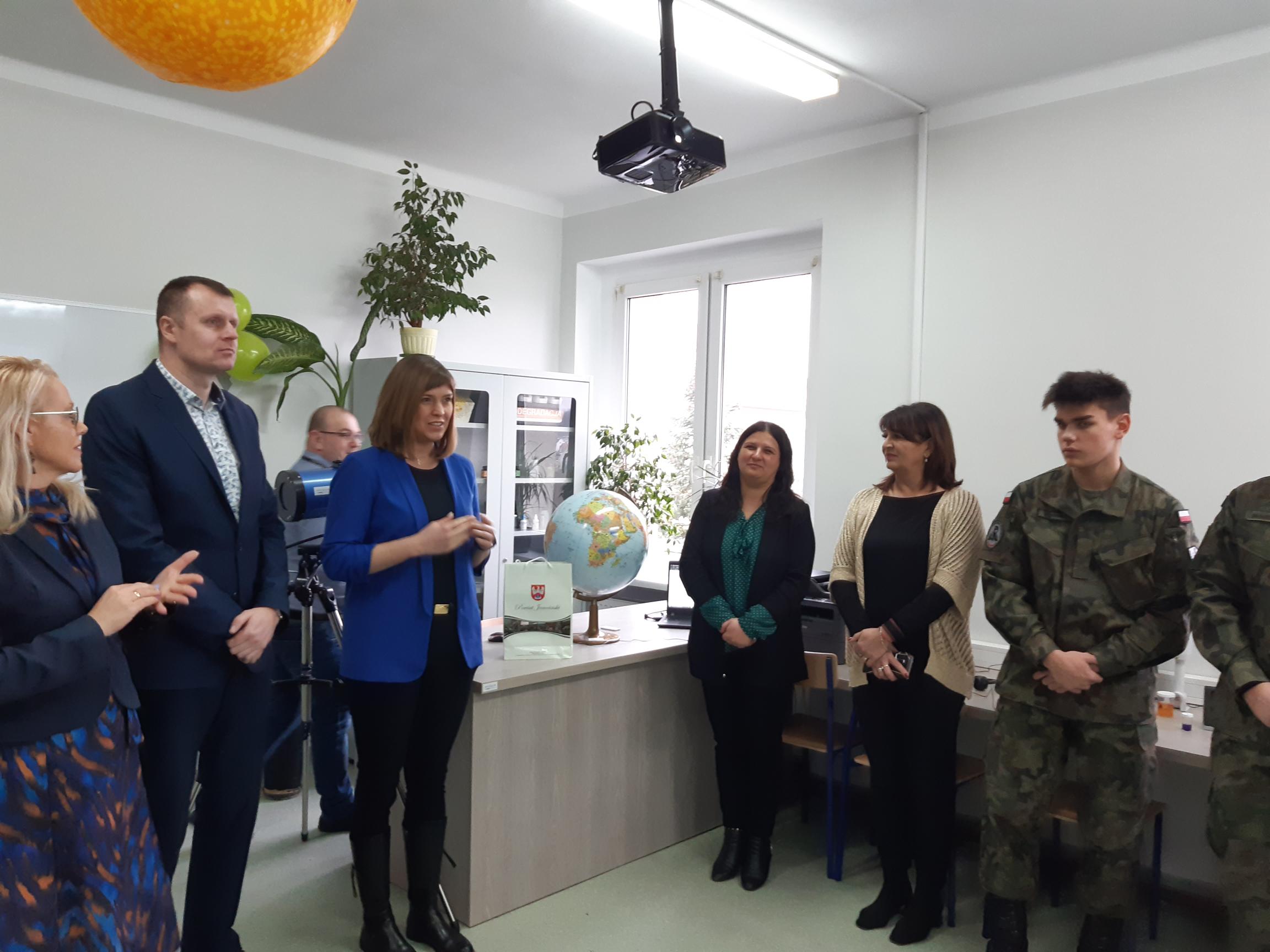 7 osób stoi w sali lekcyjnej