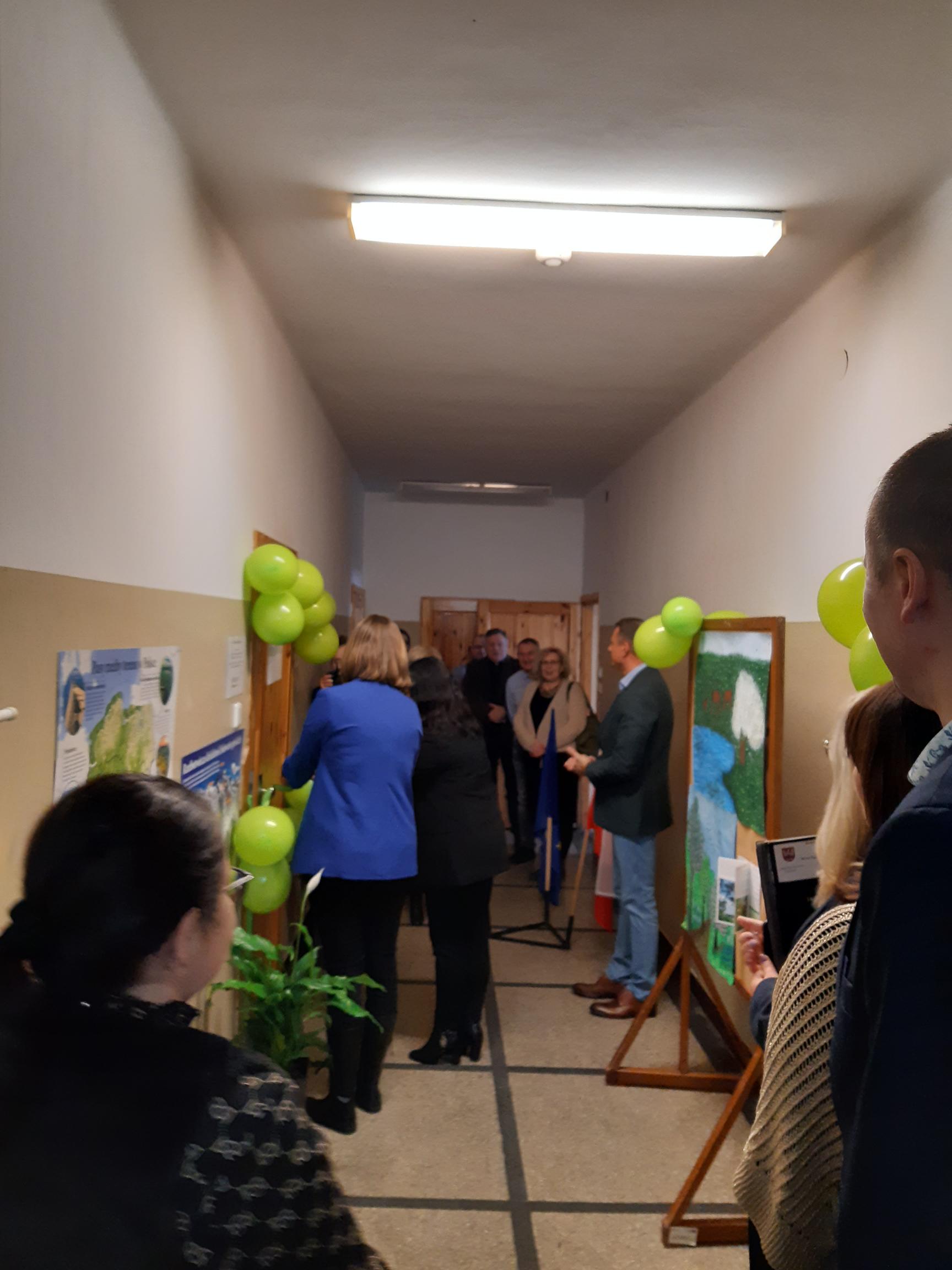 Kilka osób w hallu szkolnym otwiera salę lekcyjną