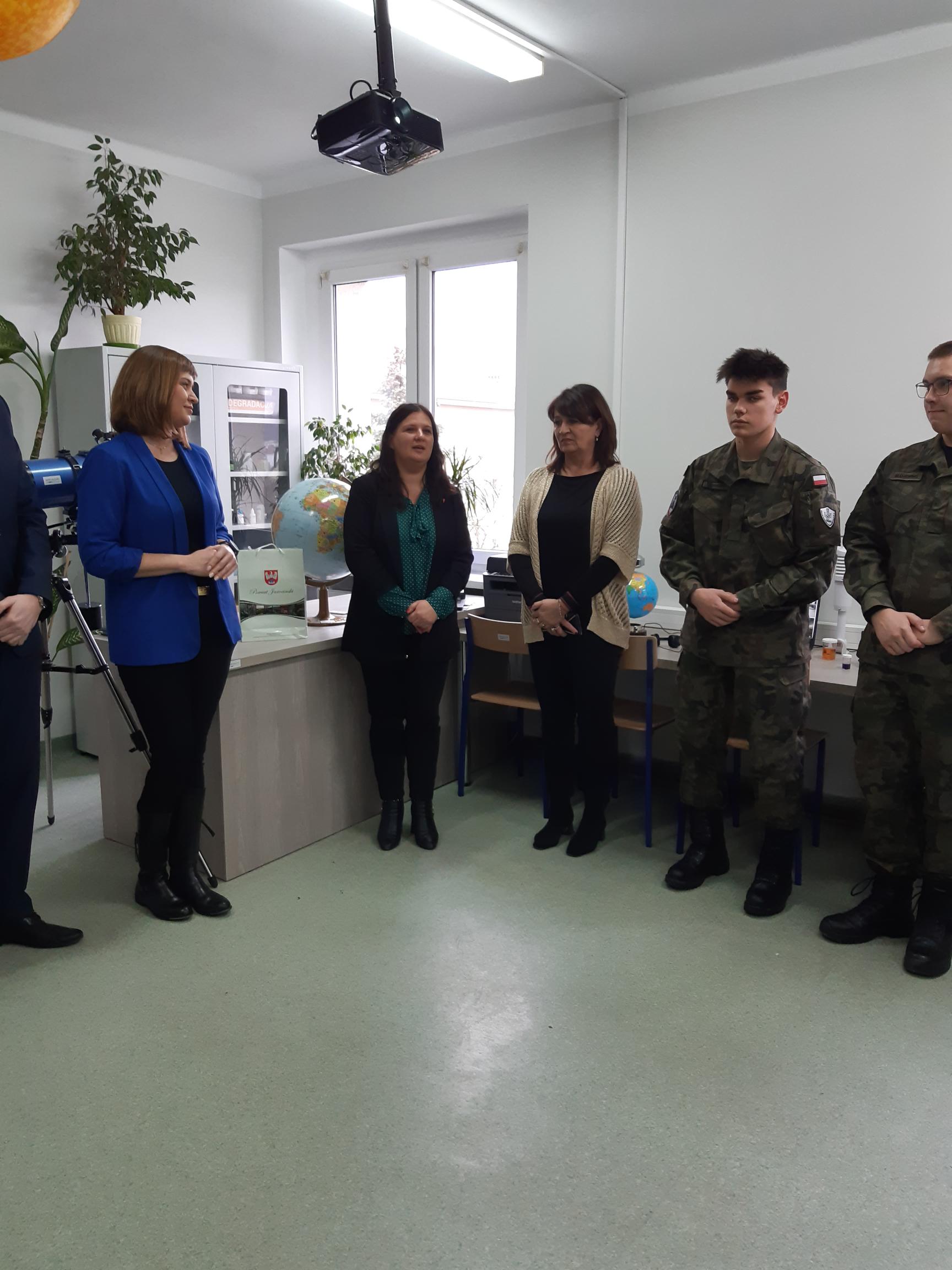 7 osób stoi w sali lekcyjnej