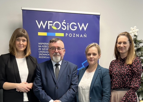 4 osoby stoją na tle ściany.