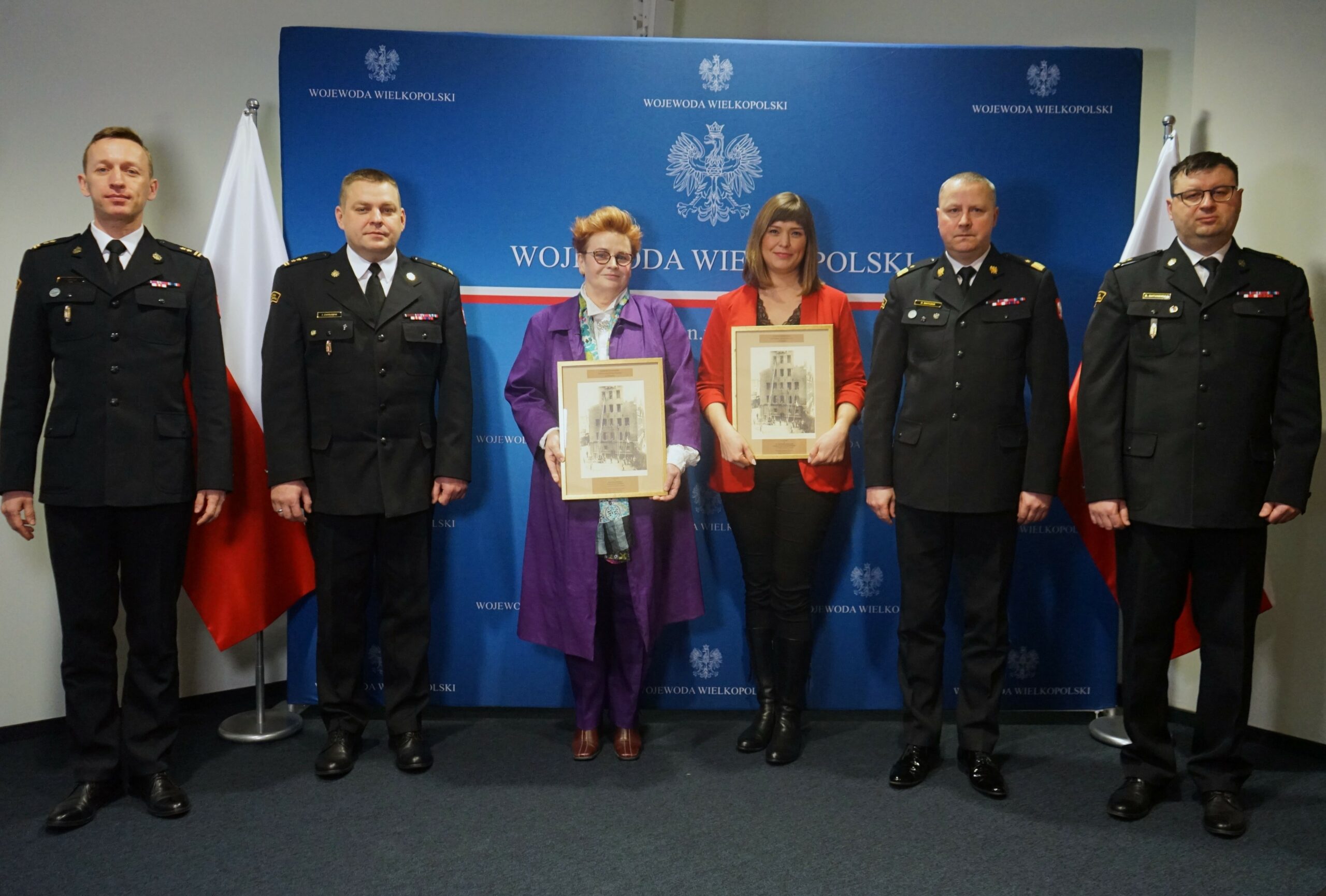 6 osób stoi na tle ściany i bannera reklamowego