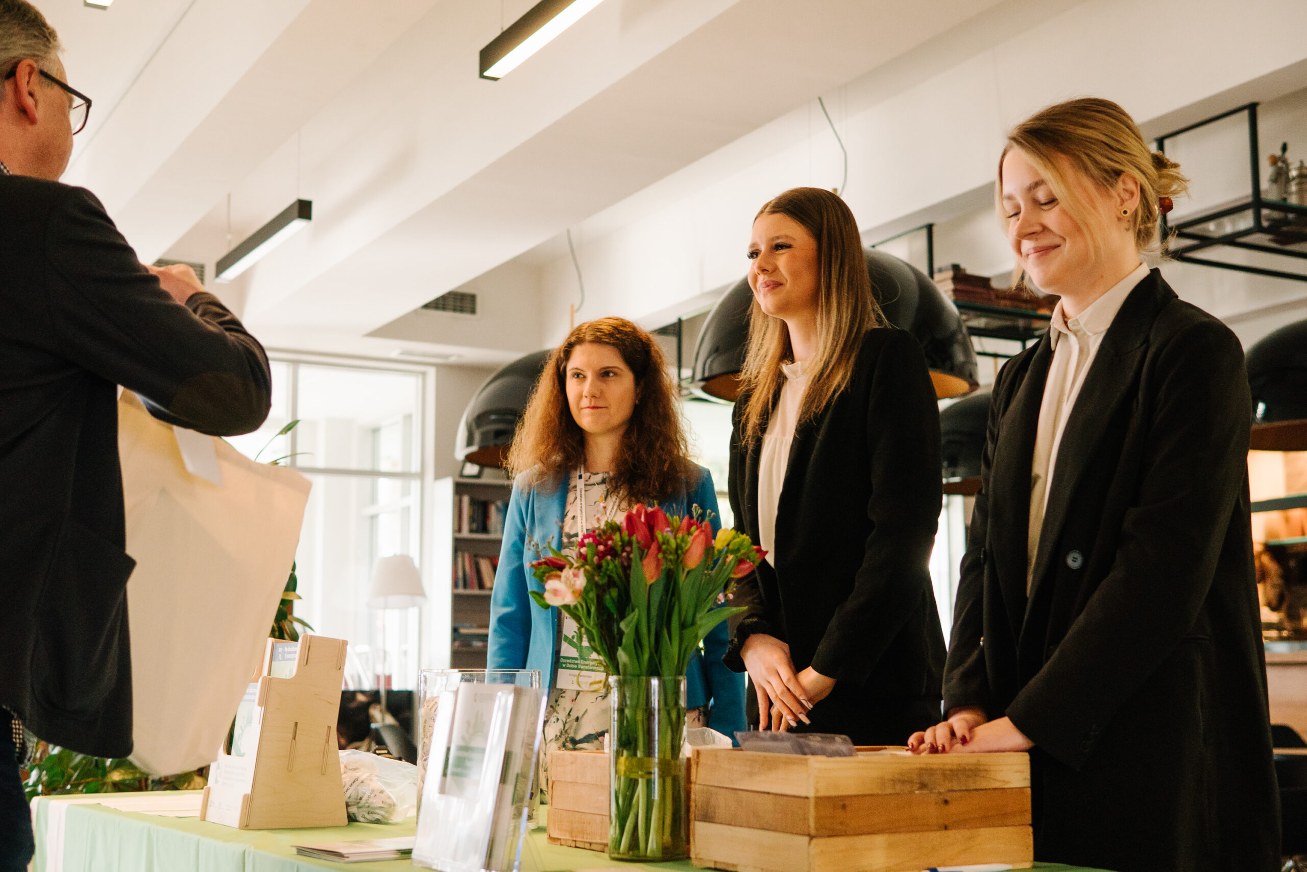 3 osoby obsługujące recepcję konferencji.