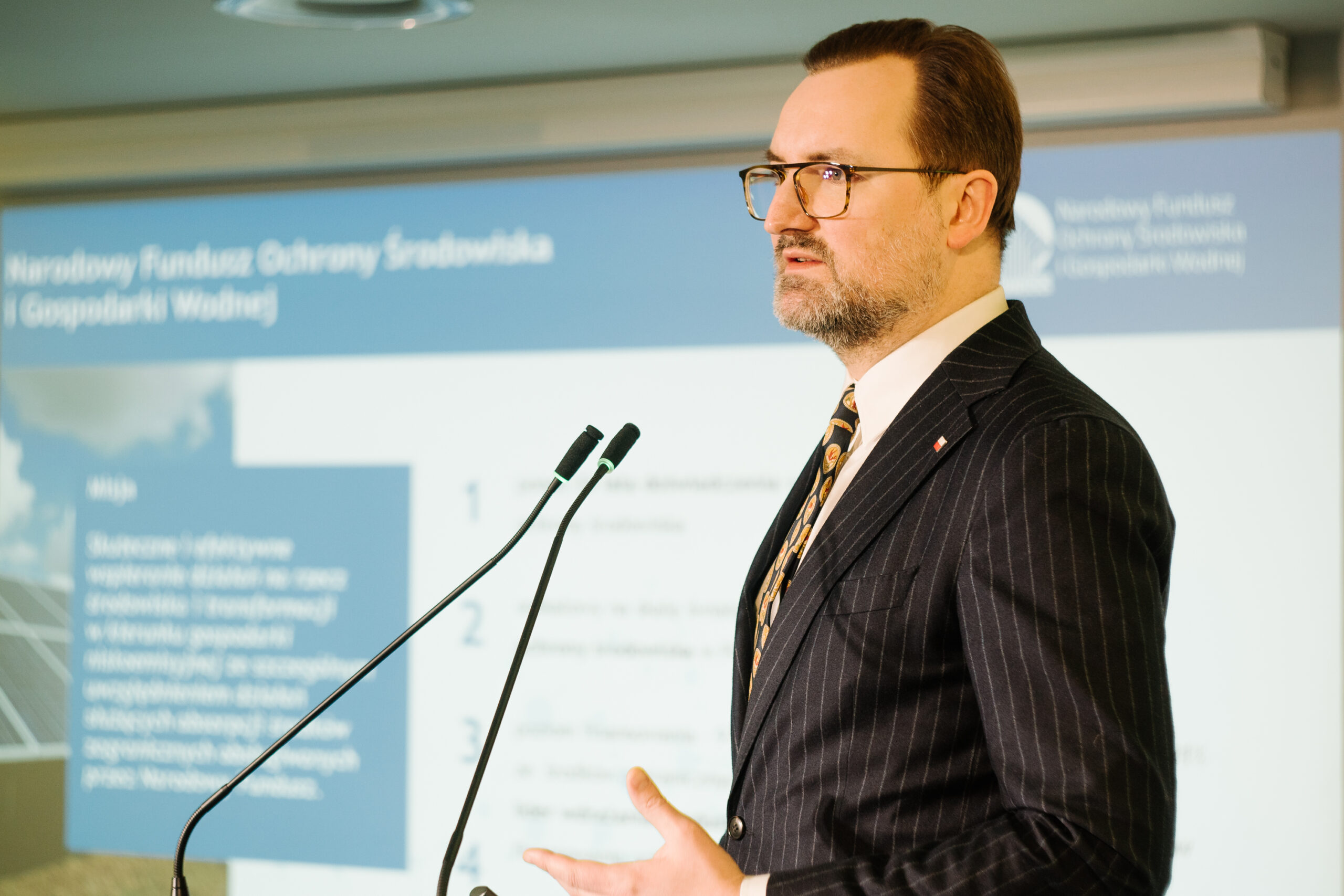 1 osoba stoi przy mównicy i przemawia na konferencji