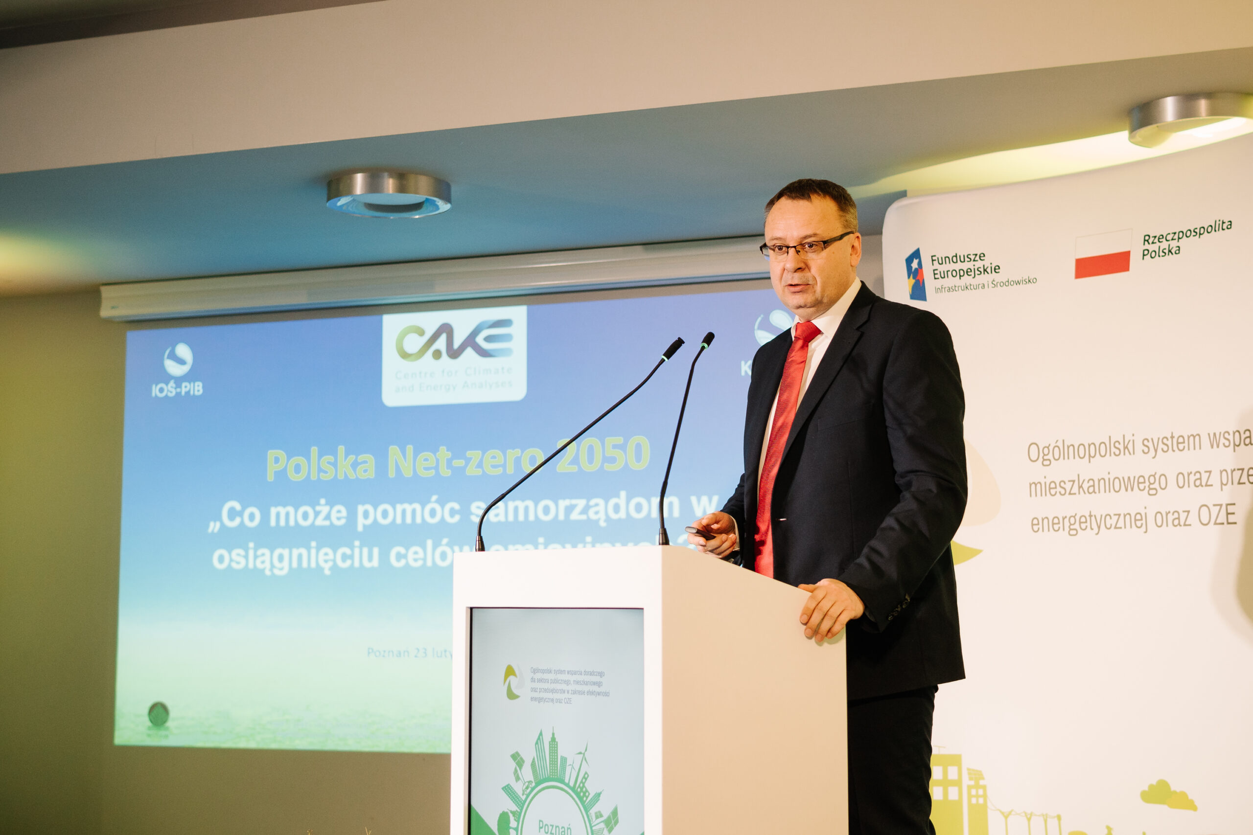 1 osoba stoi przy mównicy i przemawia na konferencji.