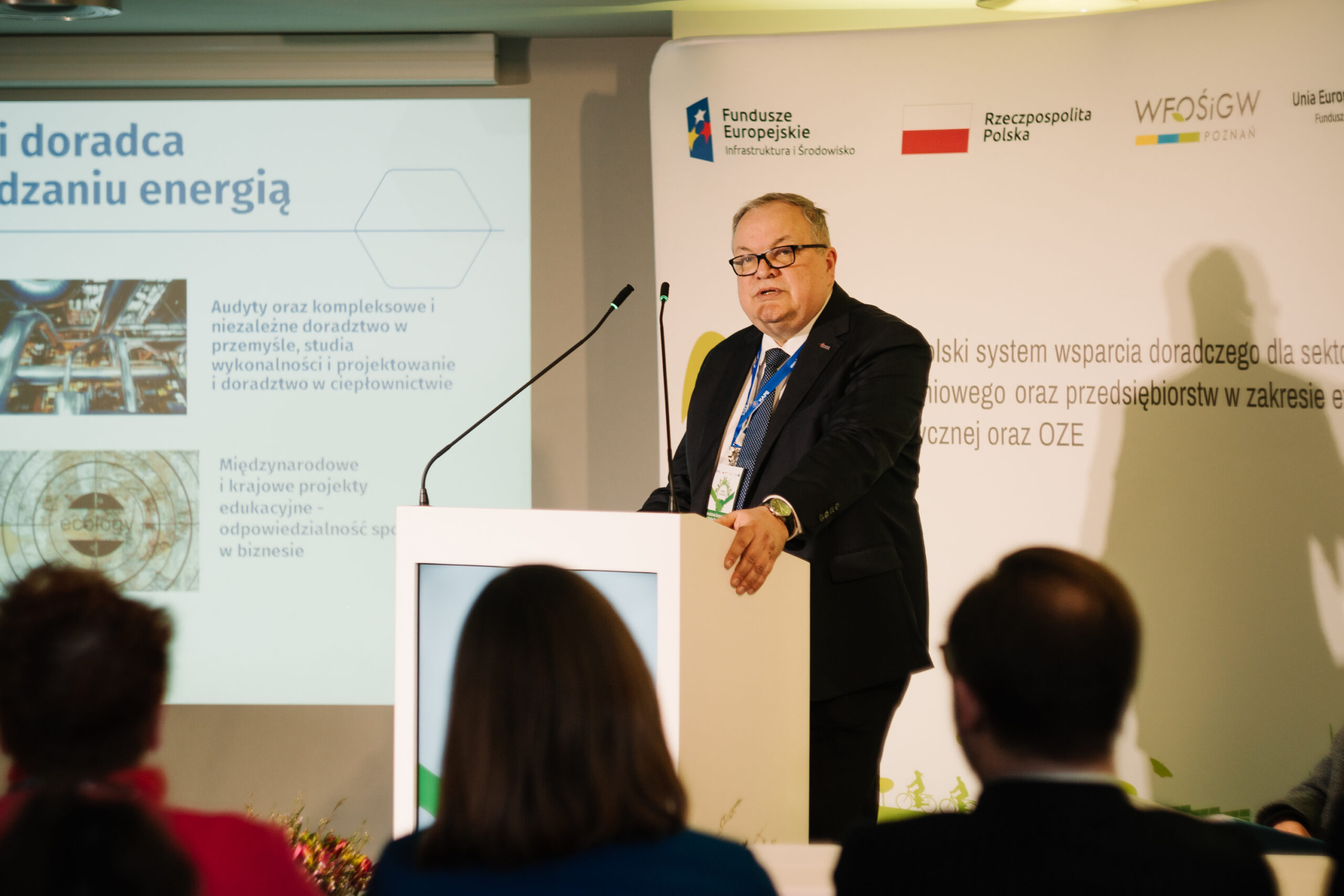 1 osoba stoi przy mównicy i przemawia na konferencji.