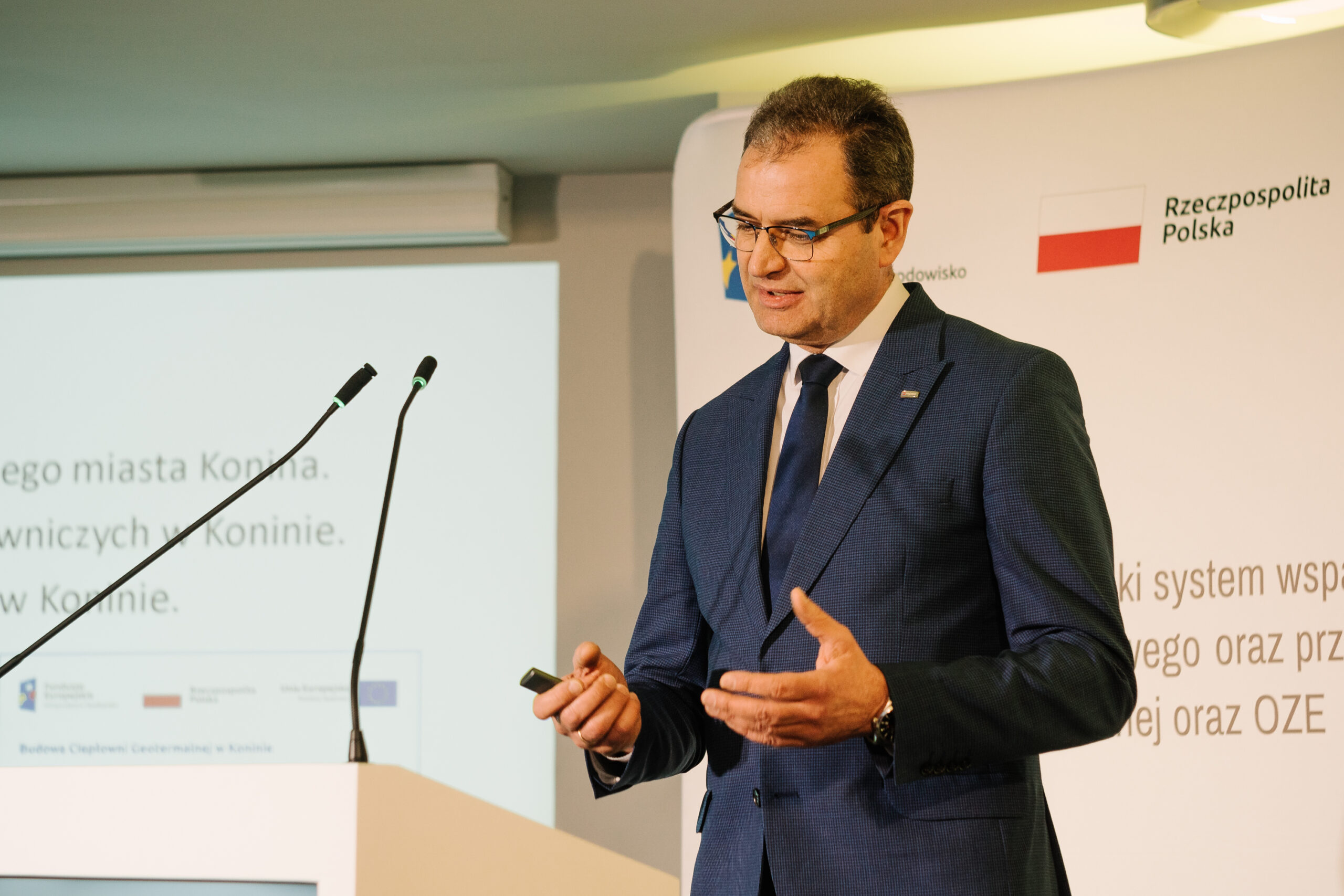 1 osoba stoi przy mównicy i przemawia na konferencji