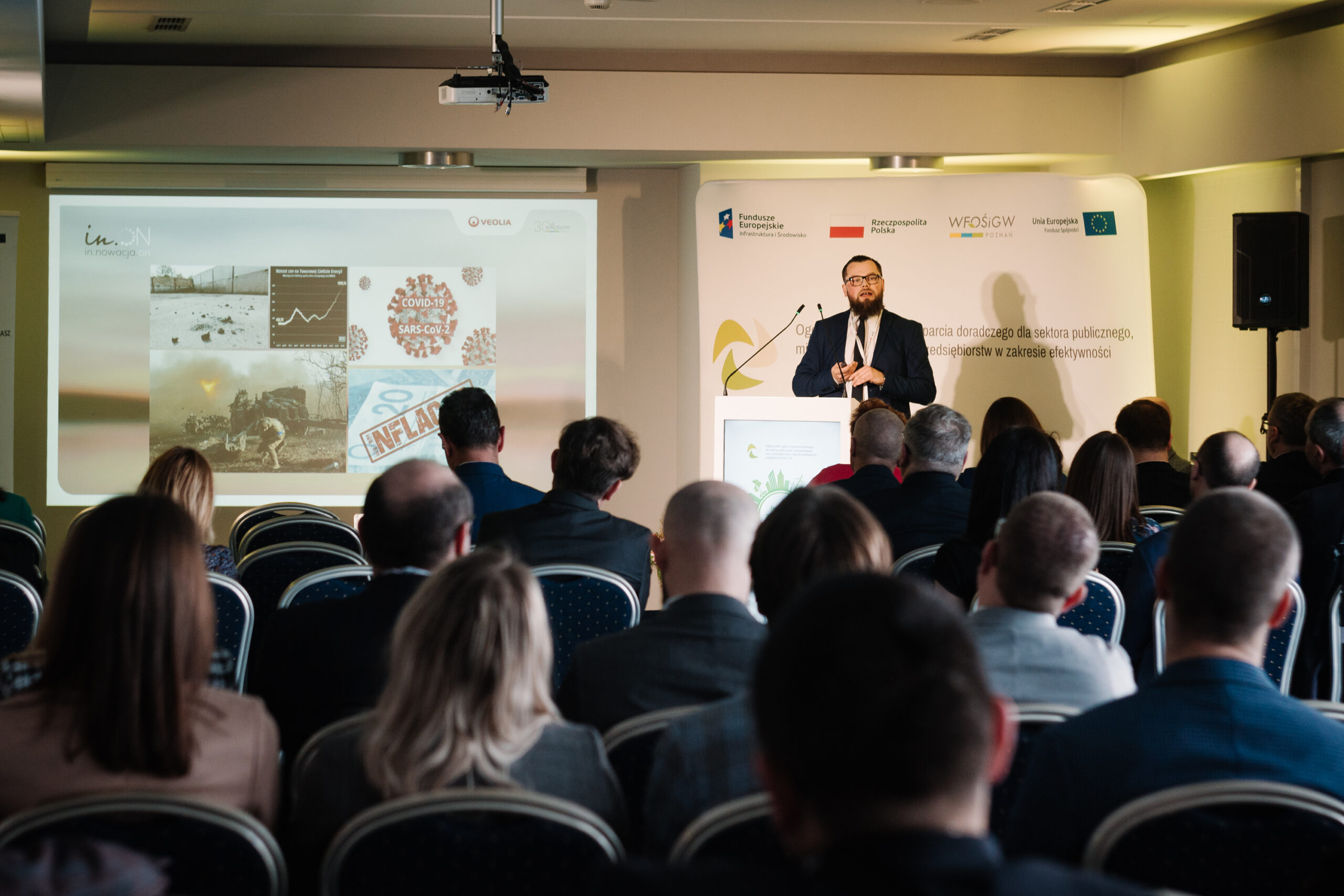 1 osoba stoi przy mównicy i przemawia na konferencji.